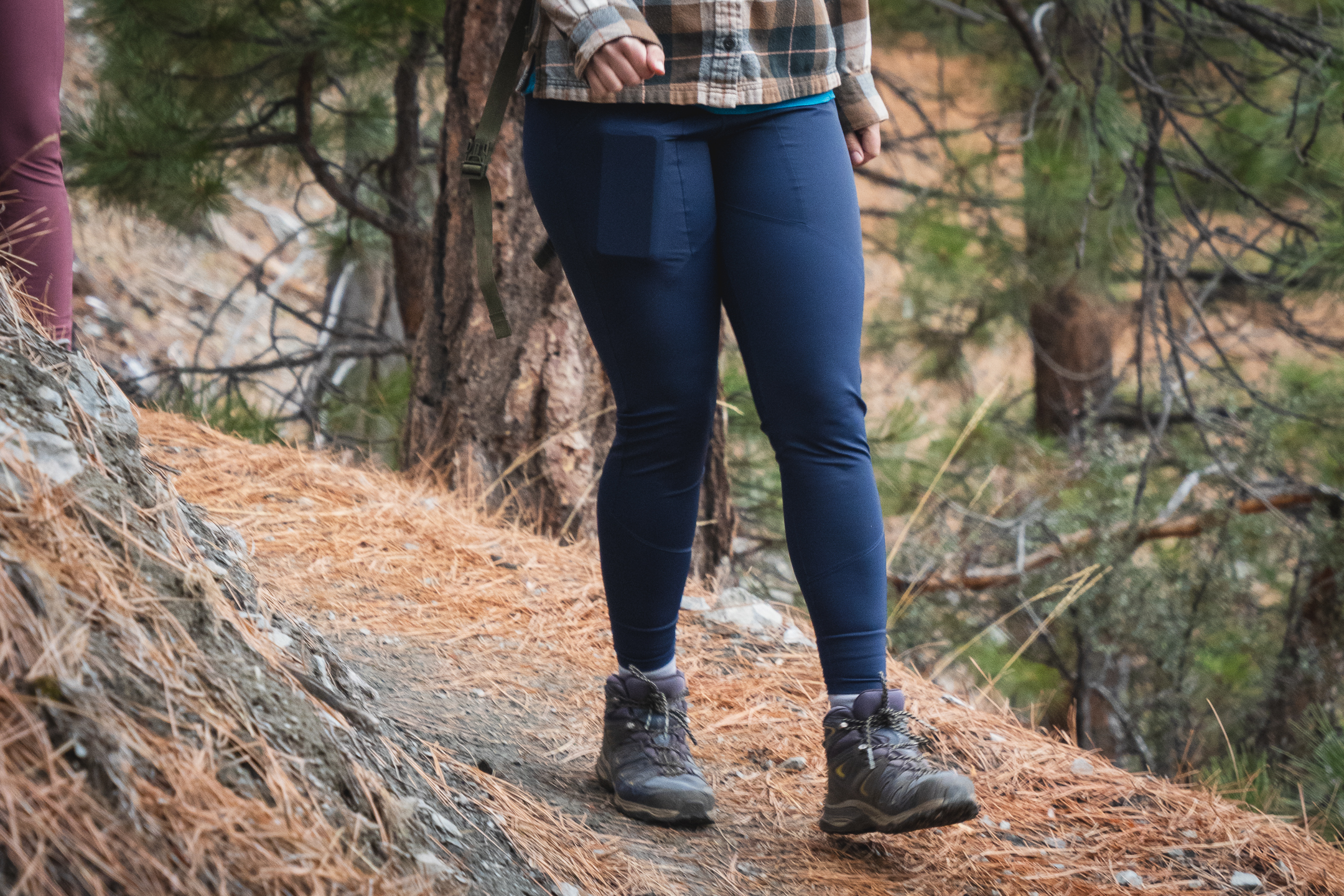 Woman hiking in dark blue athletic leggings.