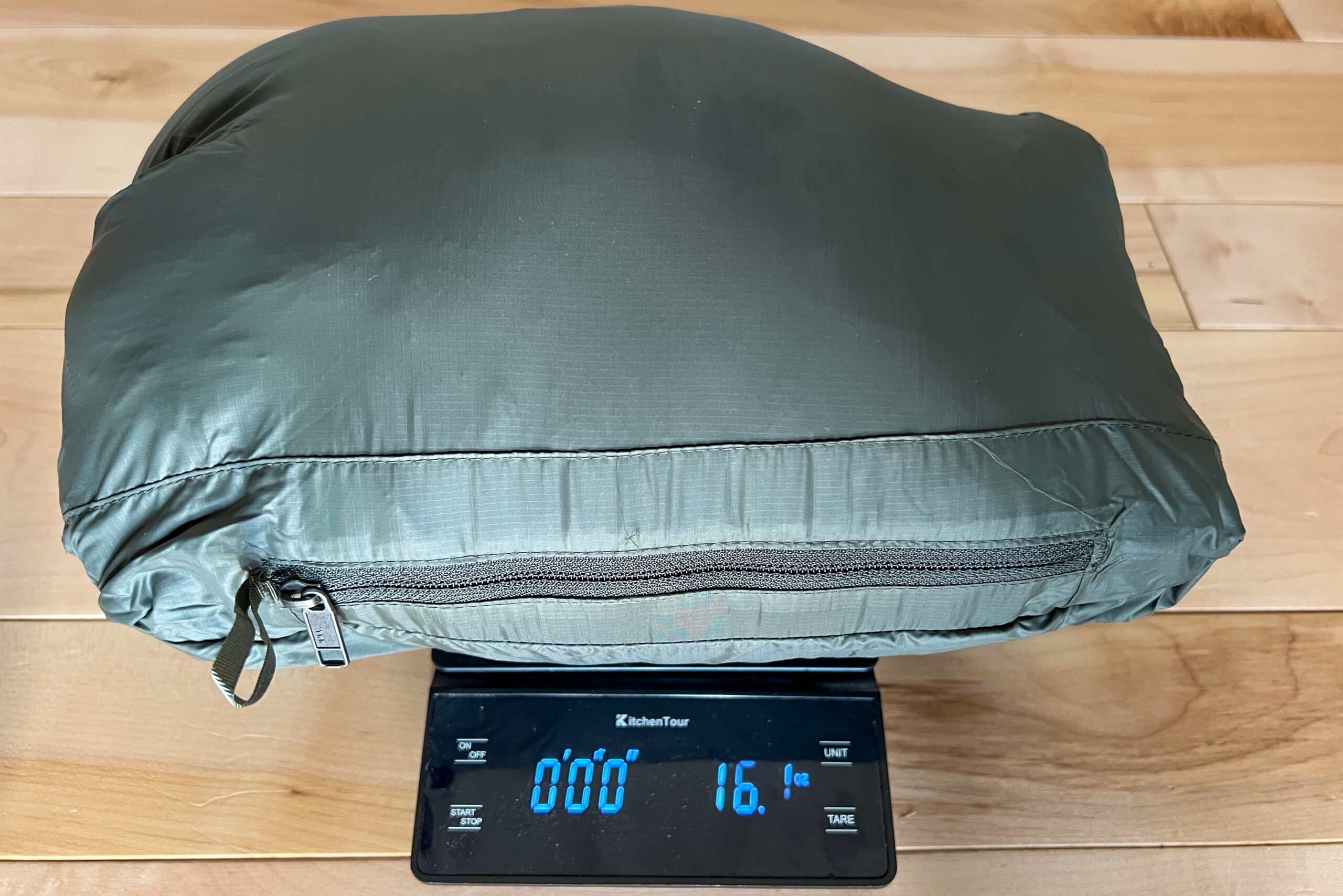 A packed Patagonia Down Sweater Hoody resting on a digital scale, showing a weight of 16.1 ounces.