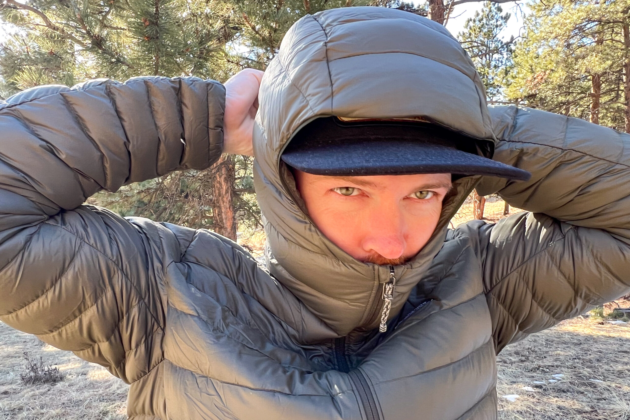 A close-up of a person pulling the hood of the Patagonia Down Sweater Hoody tightly around their head, emphasizing its insulated fit.