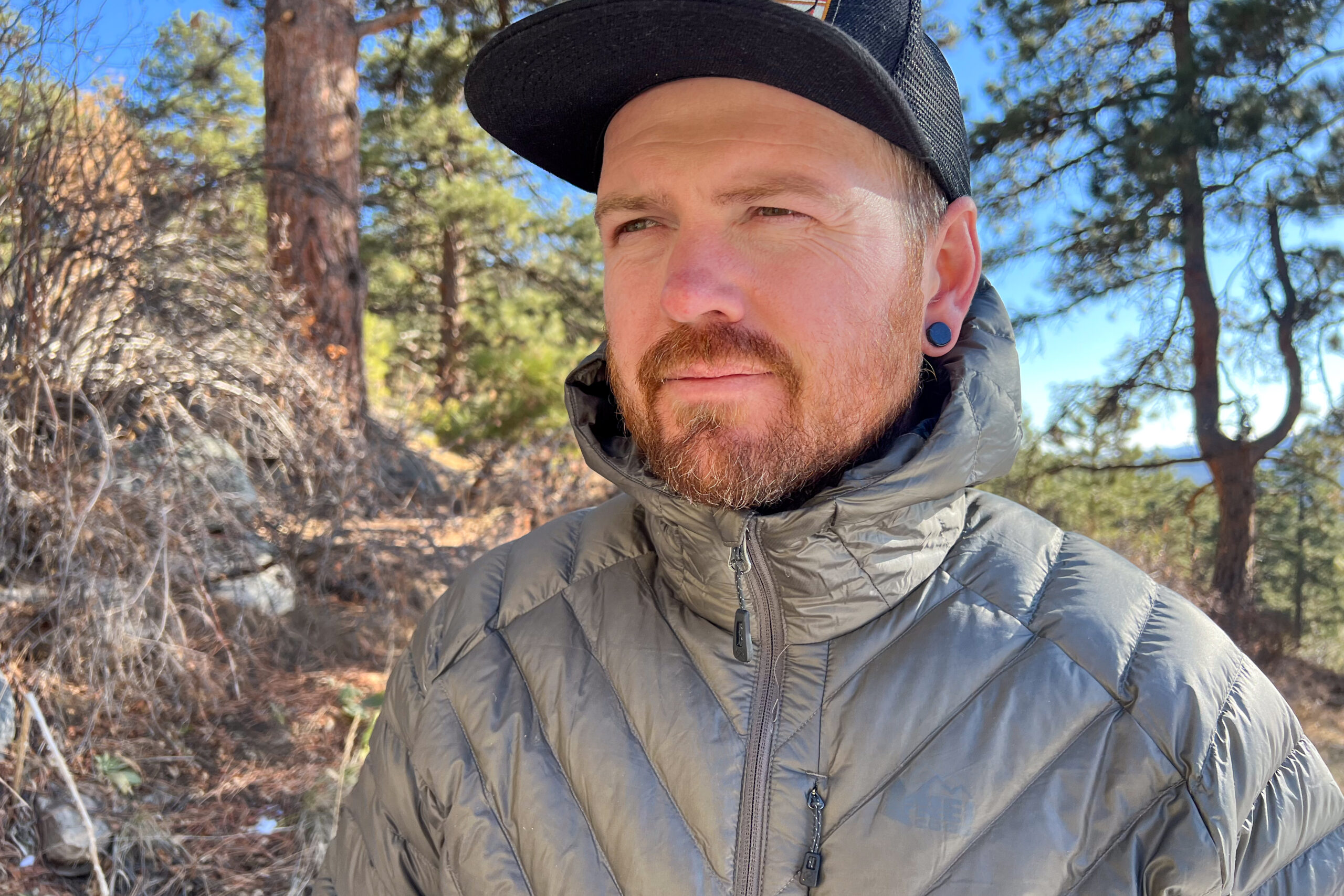 Close-up of a person wearing the REI Magma 850 Down Hoody, highlighting the insulated collar around their neck.