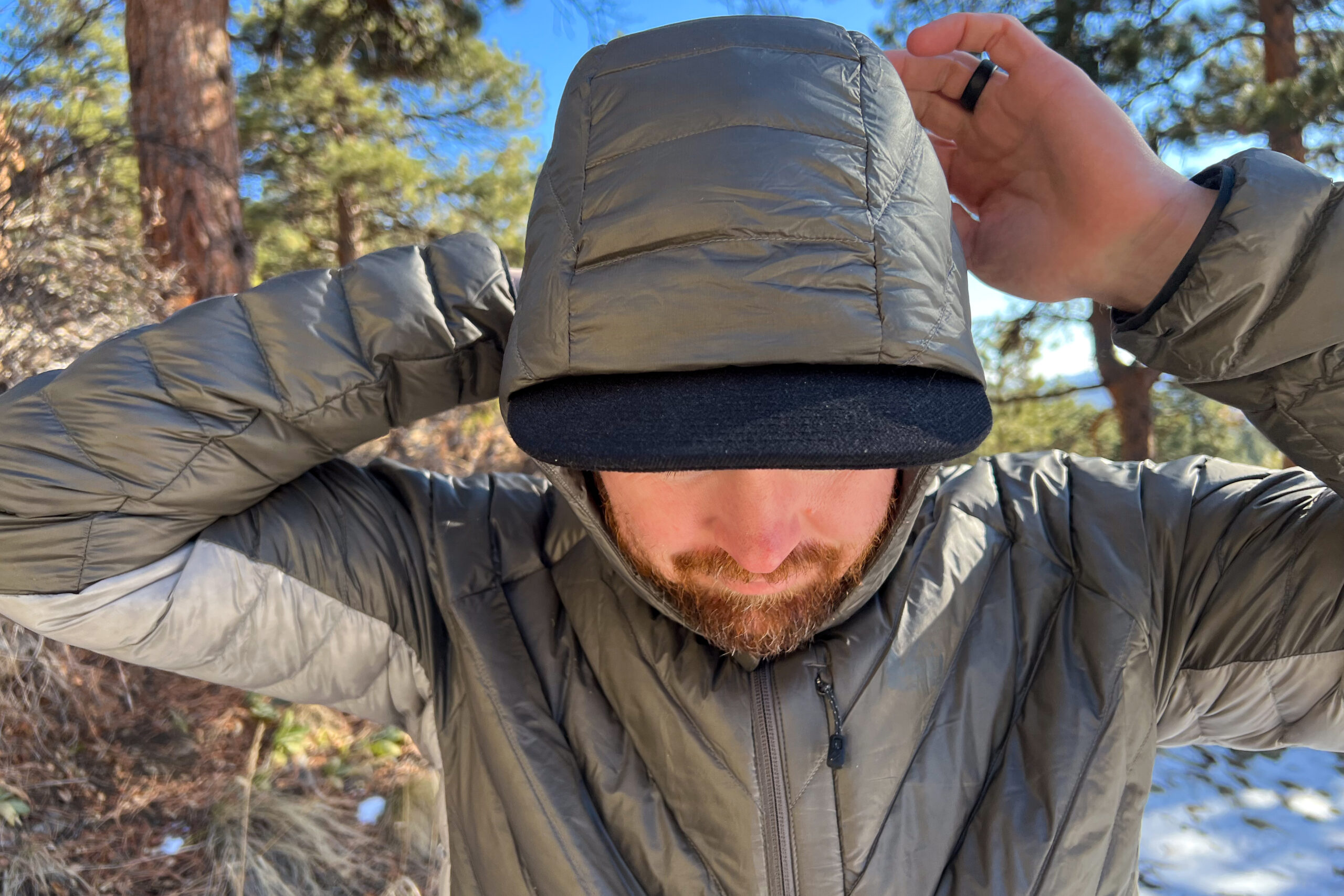 Close-up of a person adjusting the hood of the REI Magma 850 Down Hoody, showing its insulated design.