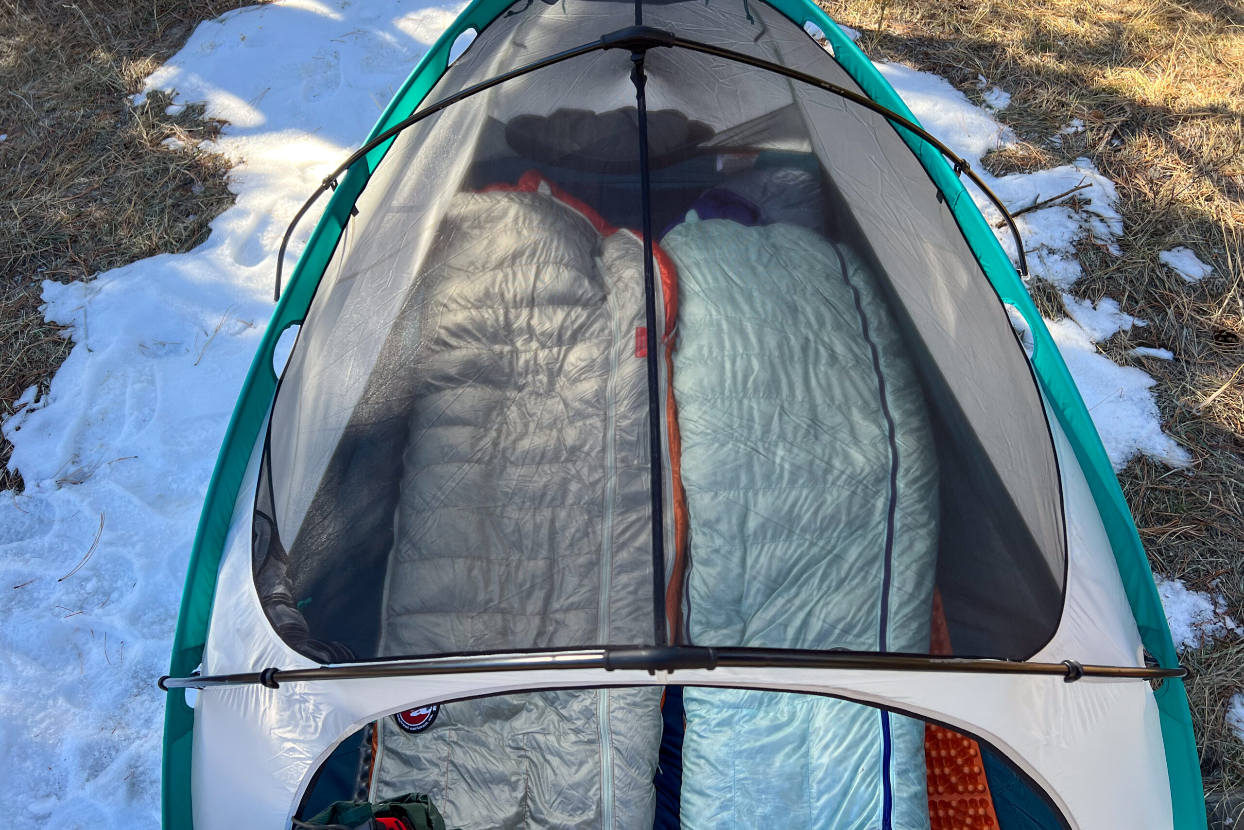 An overhead shot of a tent. The roof is made out of mesh and you can see down into the tent. There are two sleeping bags in the tent.