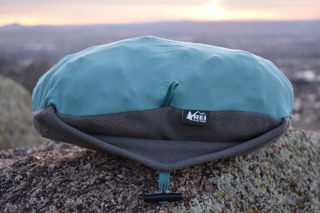 Close up of the REI Trailmade Pillow on a boulder as the sun sets in the background. The pillow looks lumpy due to the foam blocks inside.