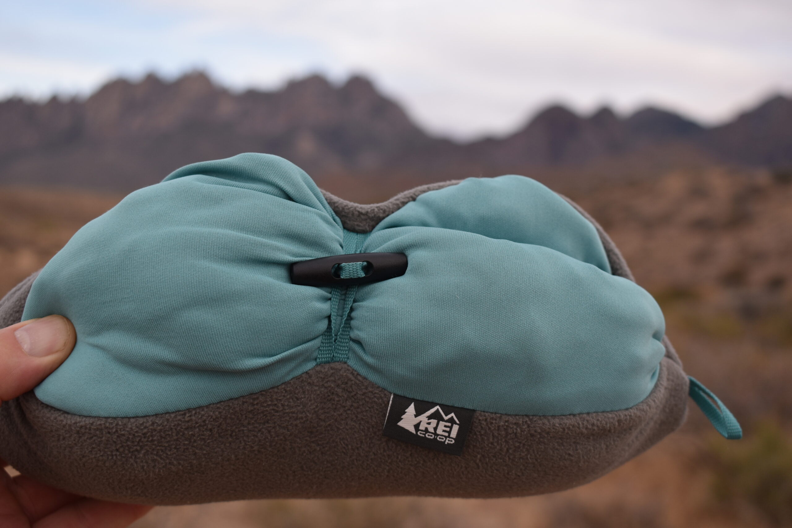 Close up of the REI Trailmade Mummy Bag Pillow with blurred mountains in the background