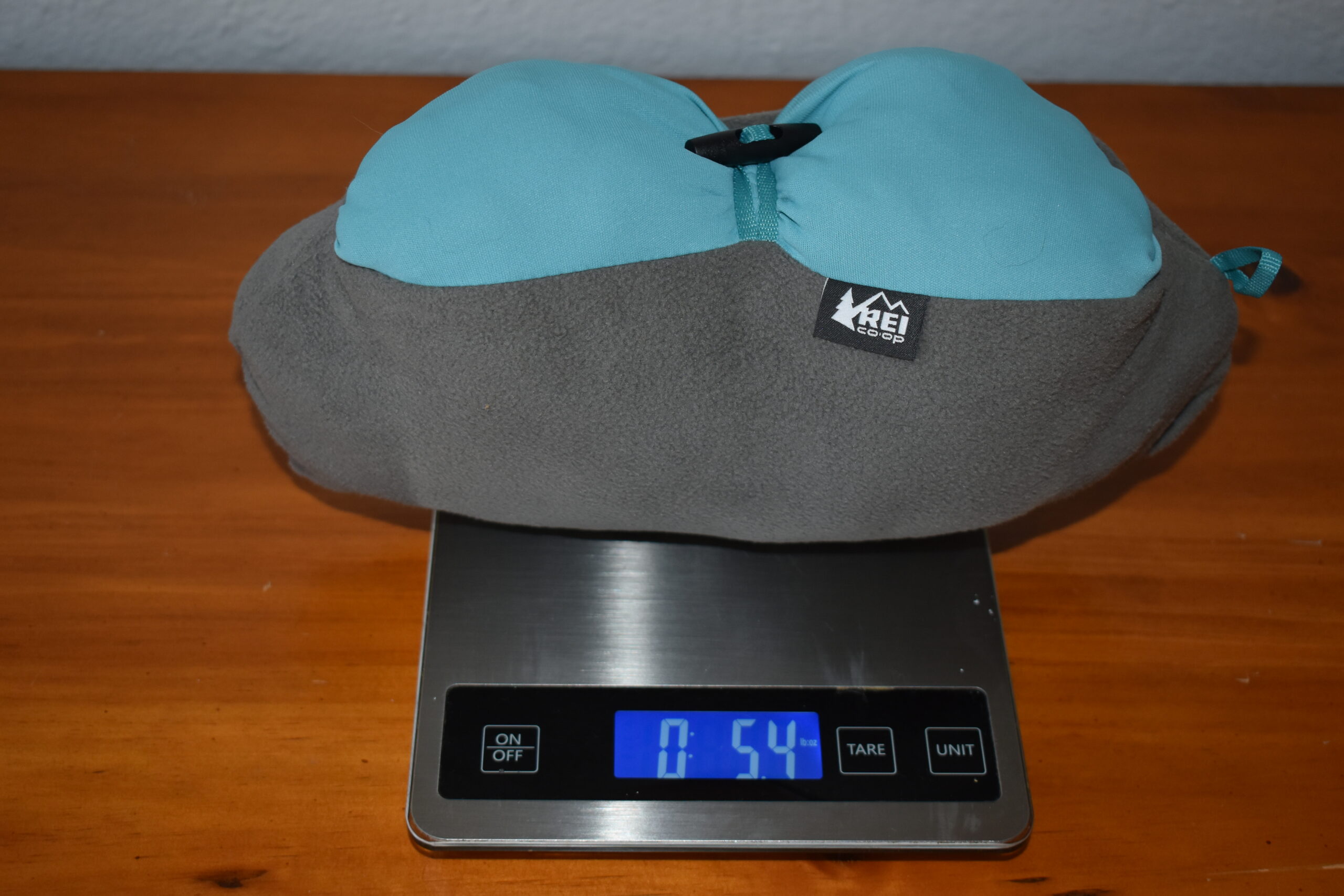 The REI Trailmade Mummy Bag Pillow on a kitchen scale that displays a weight of 5.4 ounces