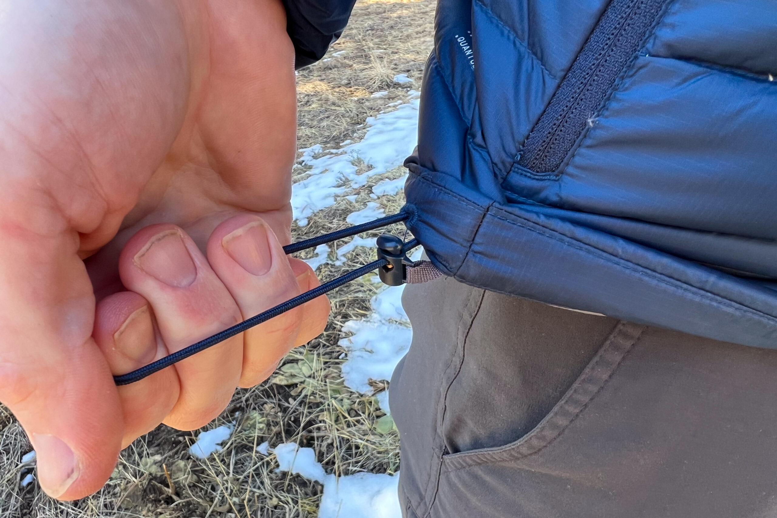 A close-up of the adjustable hem cinch on the Rab Microlight Alpine jacket, demonstrating its ability to lock in warmth.