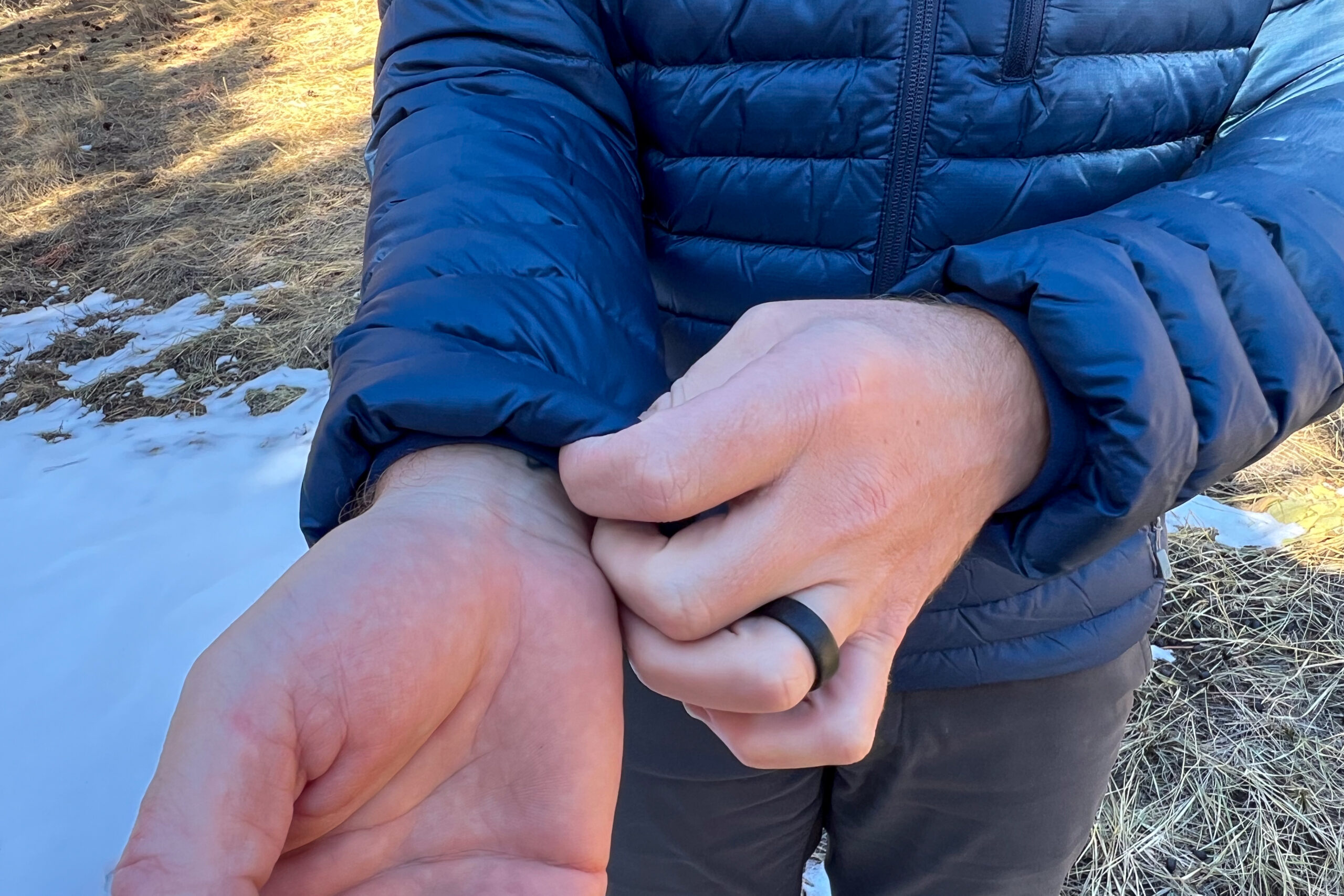 Close-up of a person adjusting the Rab Microlight Alpine jacket's elastic cuff to show its snug and secure fit.