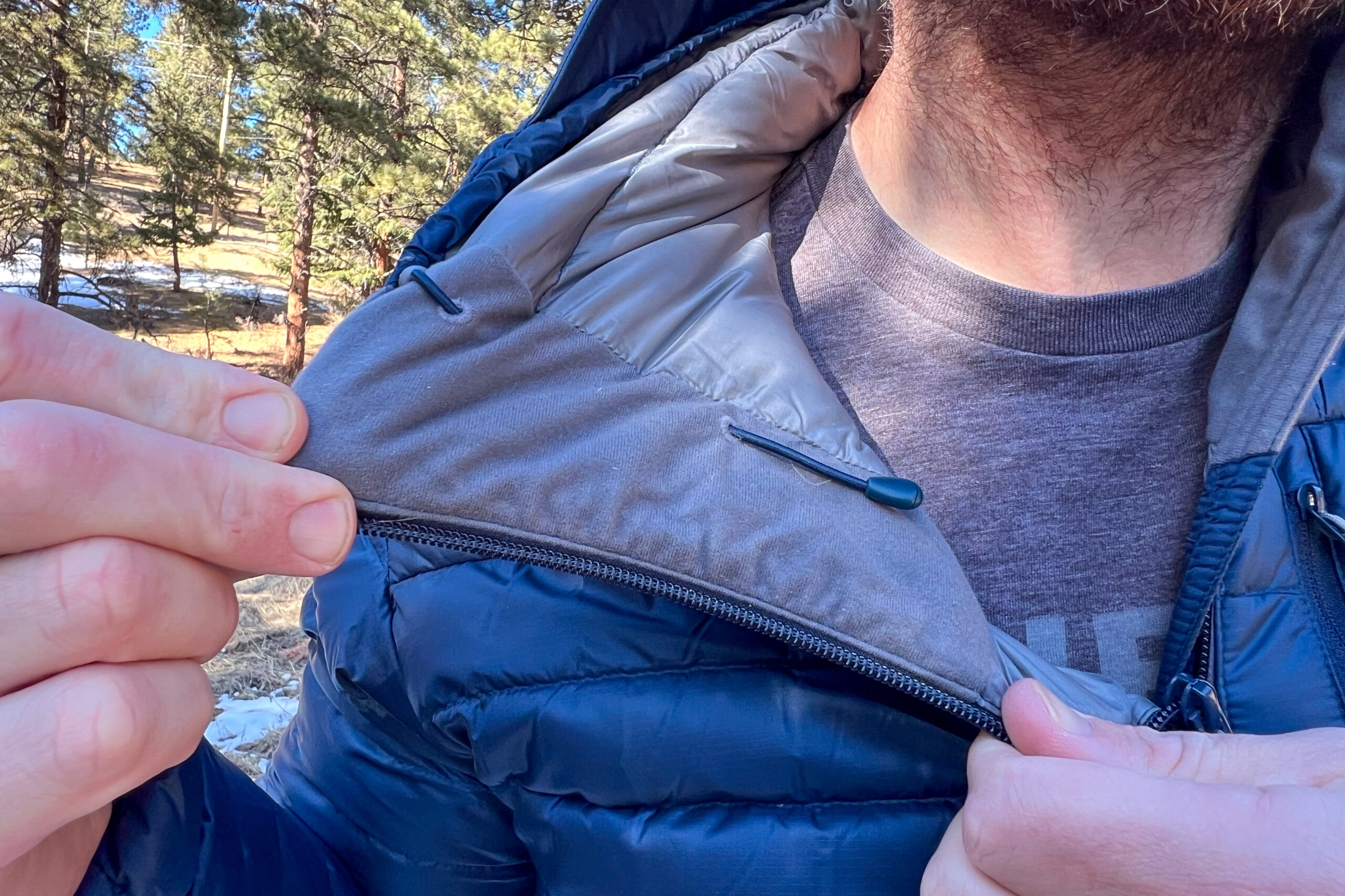 Close-up of a person pulling back the fleece-lined collar of the Rab Microlight Alpine jacket to show its soft interior fabric.