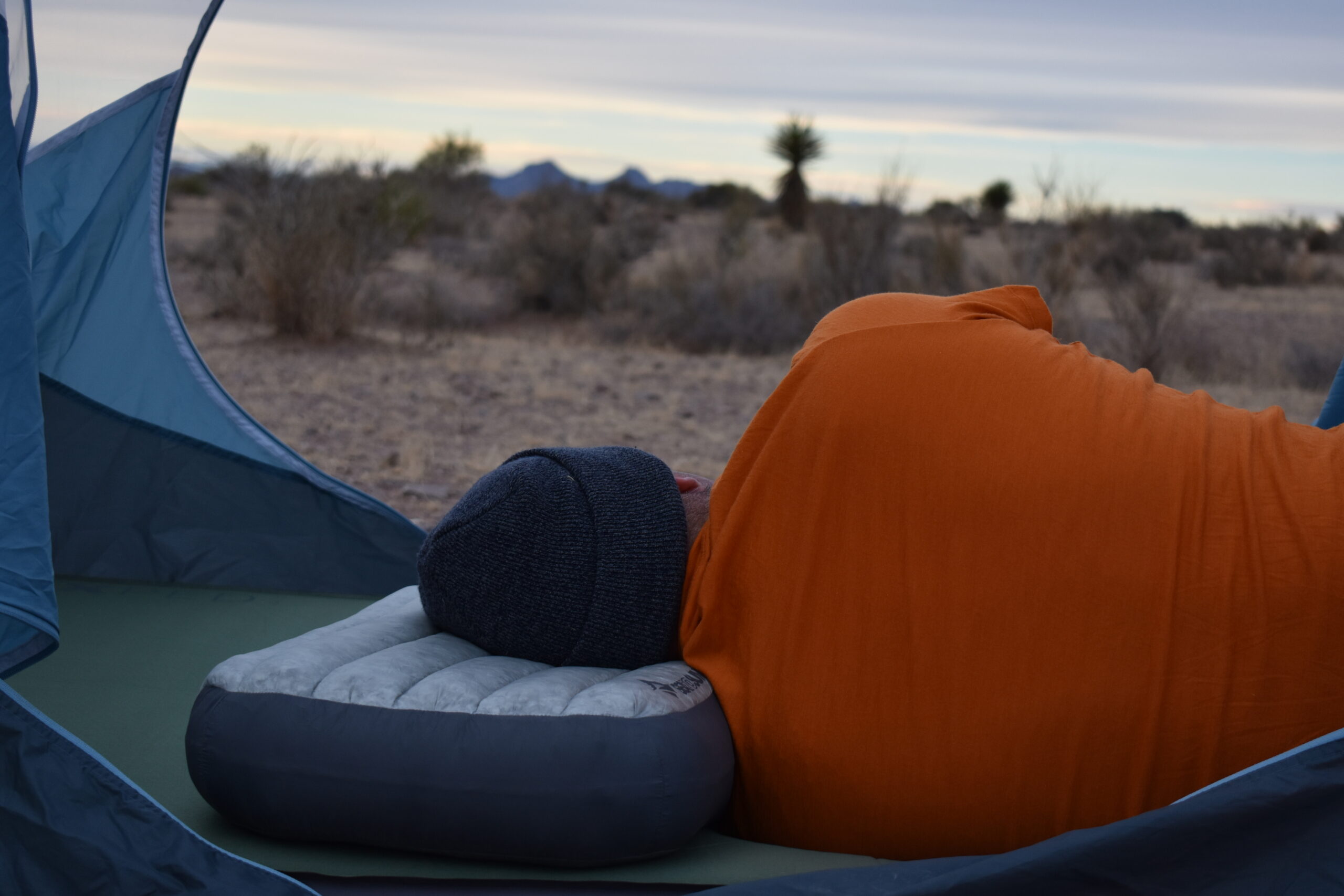 The authors sleeps on his side in the desert while resting on the Sea to Summit Aeros Down Deluxe pillow