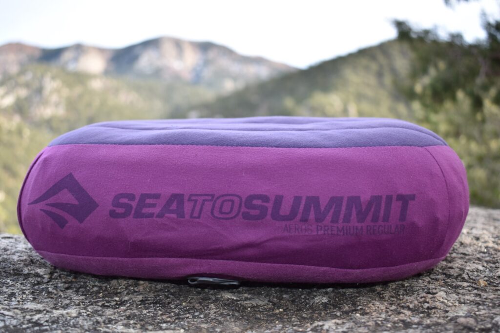 Close up shot of Sea to Summit Aeros Premium Regular Pillow sitting on a boulder with blurred mountains in the background