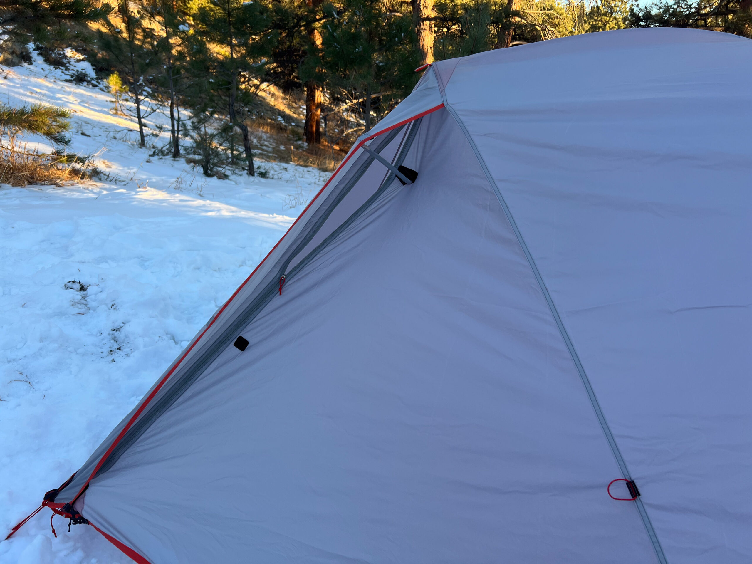 A shot of a tent that has been pitched on snow. The door is propped open with a kickstand vent.