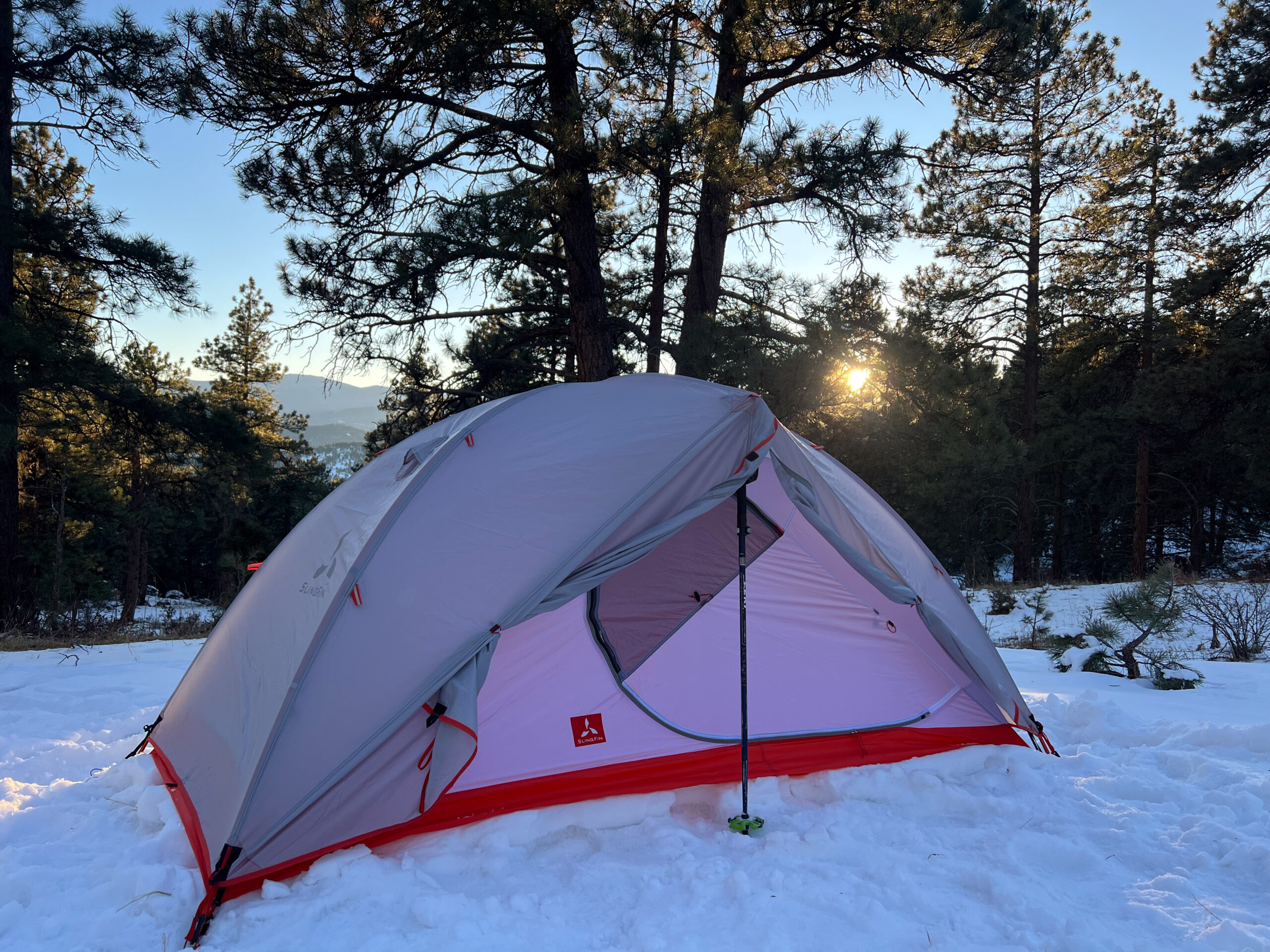 SlingFin CrossBow 2 tent with an open door revealing its interior in a snow-covered forest.