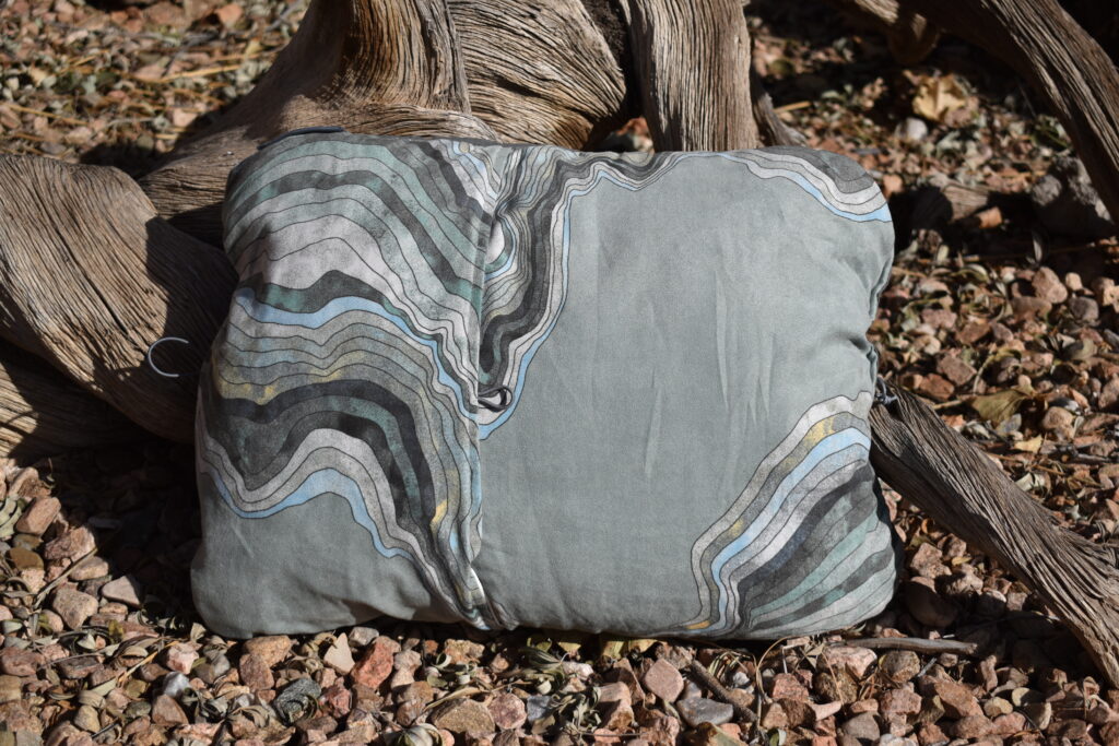 Close up of the Therm-a-rest Compressible Pillow propped up by a piece of twisted driftwood