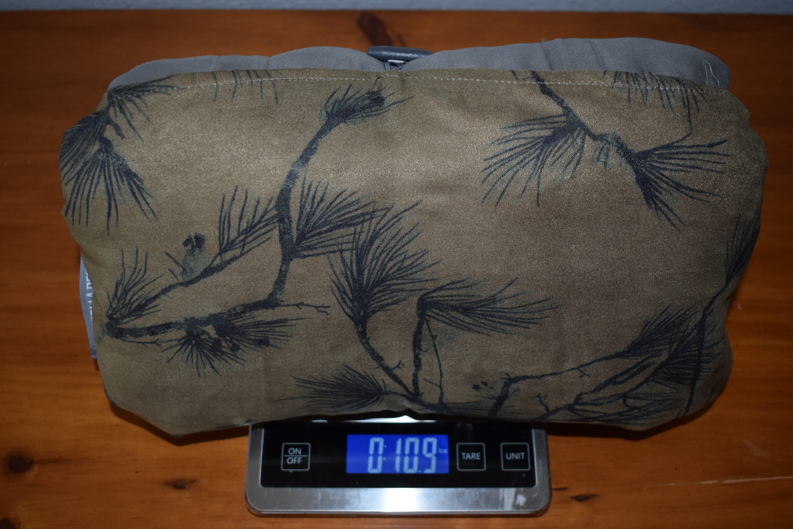 The Compressible Cinch pillow setting on a kitchen scale that reads 10.9 ounces