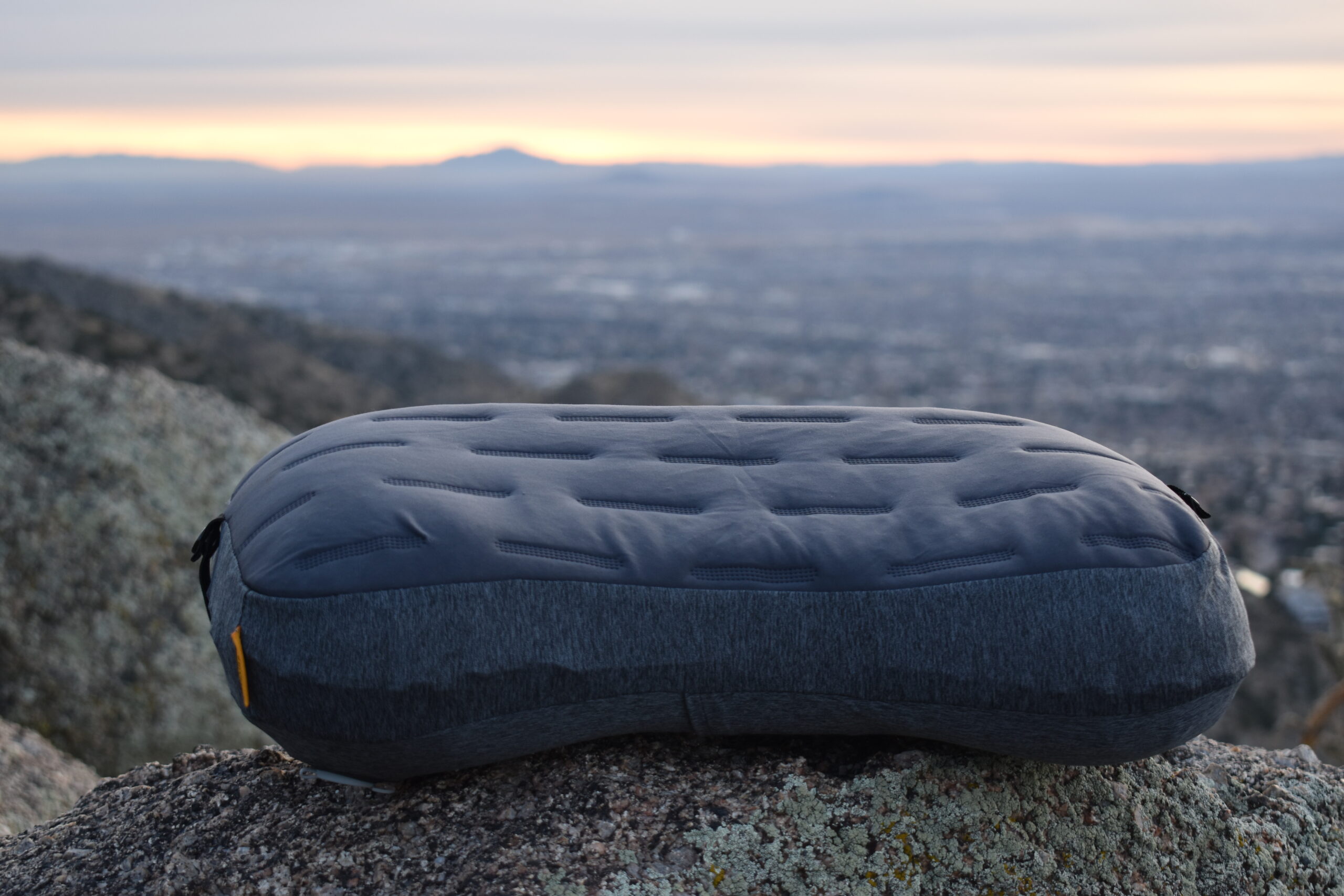 Trekology camp pillow lying on a boulder with a volcanic horizon in the background