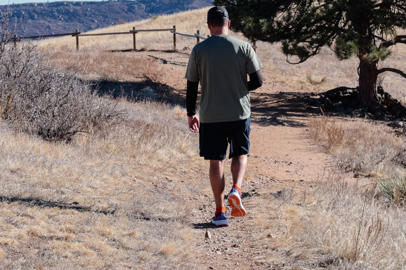 Man walking down a trail with back to the camera.