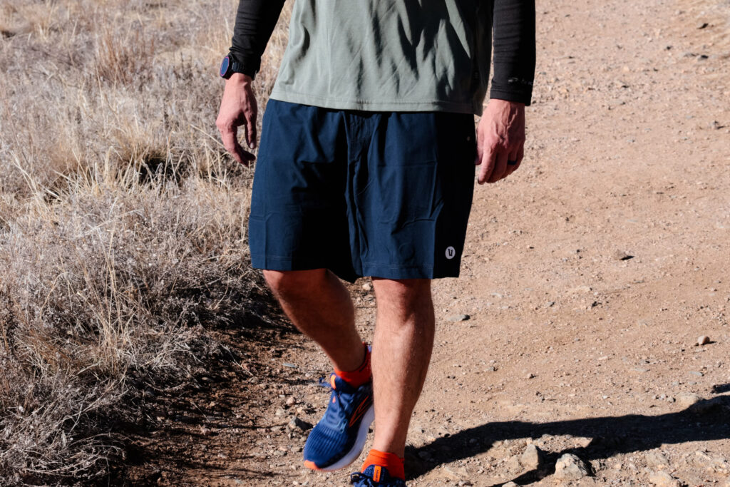 Man walks down a trail in blue shorts.