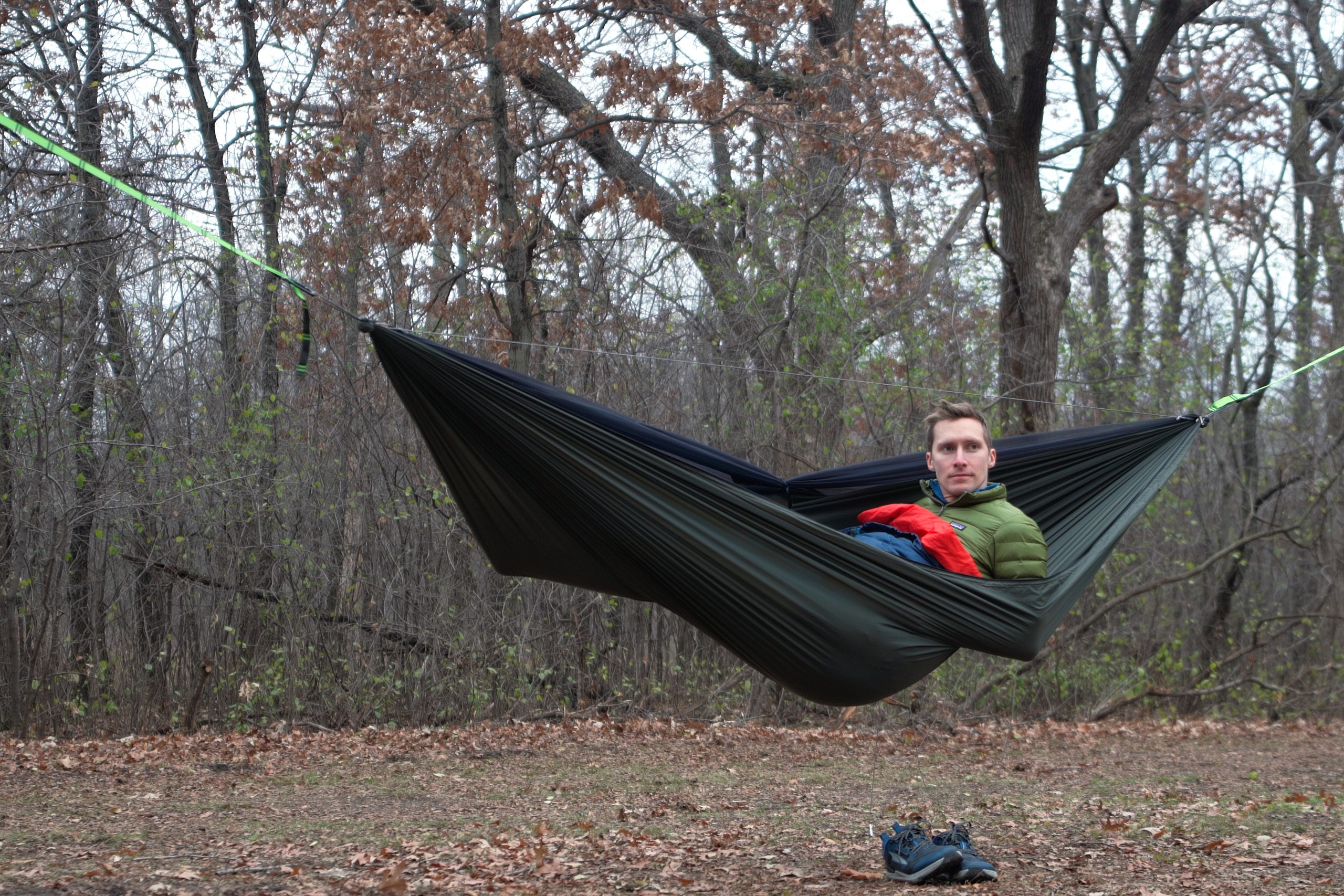 A man sits up in a green hammock