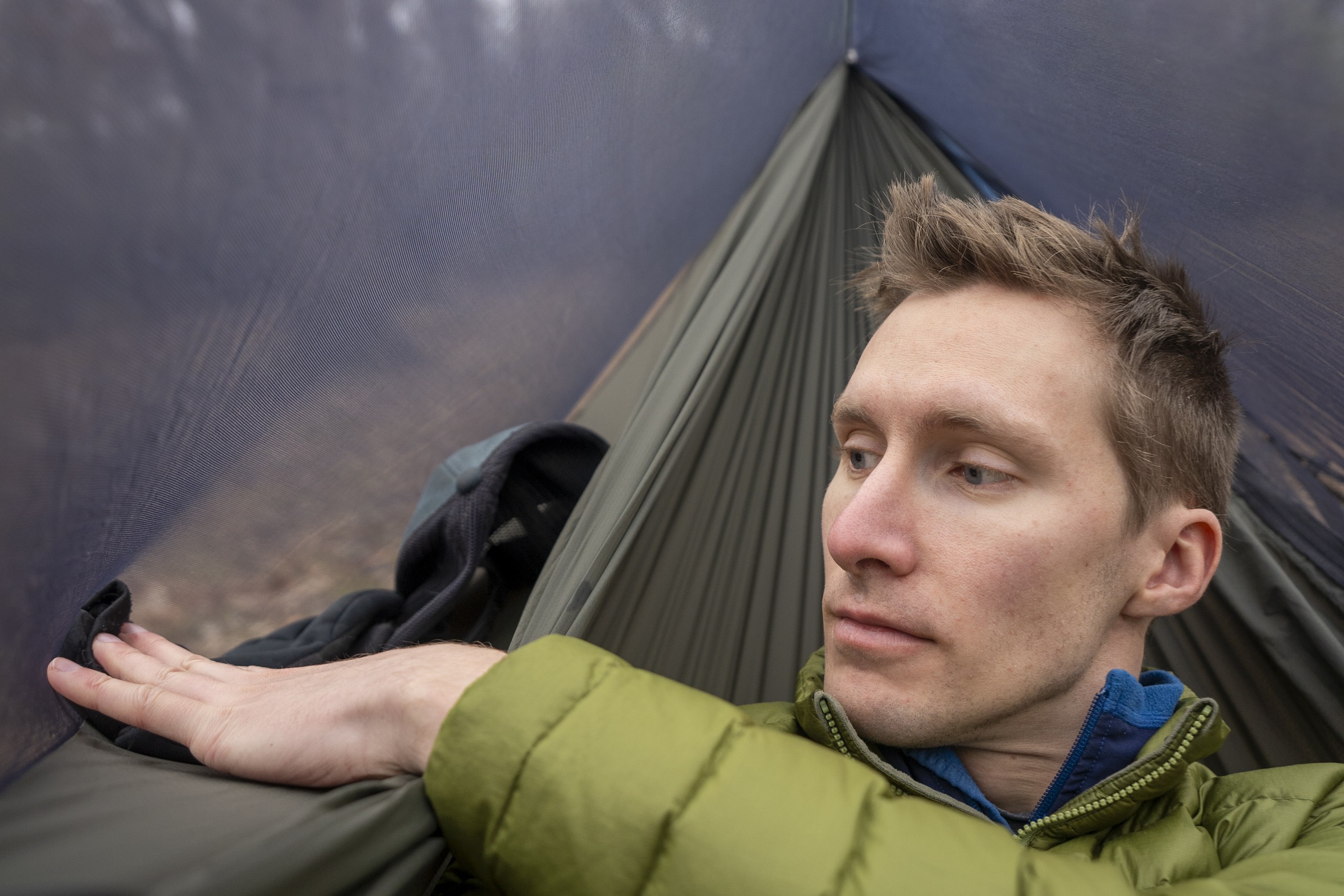 A man puts a hand into a side pocket of a hammock