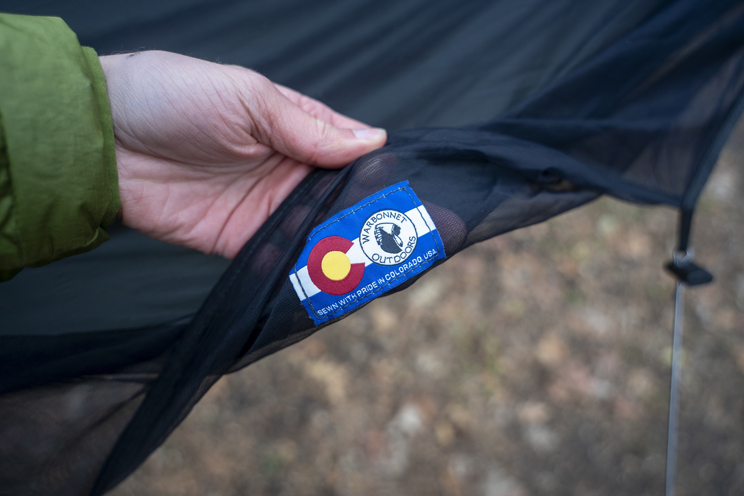 A hand holds a logo of a hammock brand