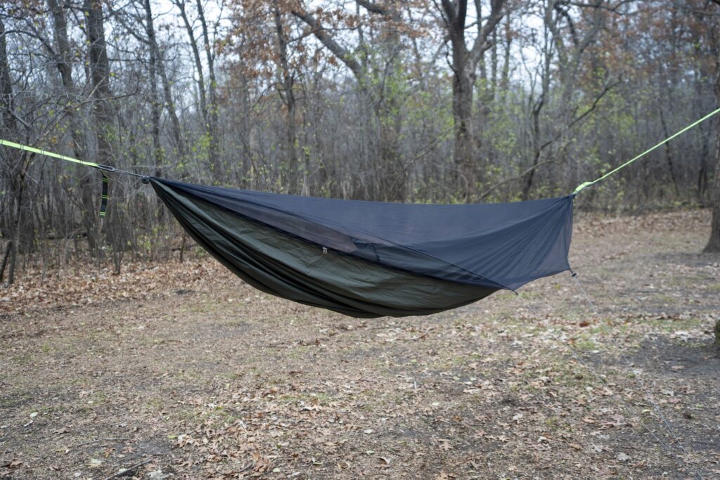 A green hammock in a forest clearing