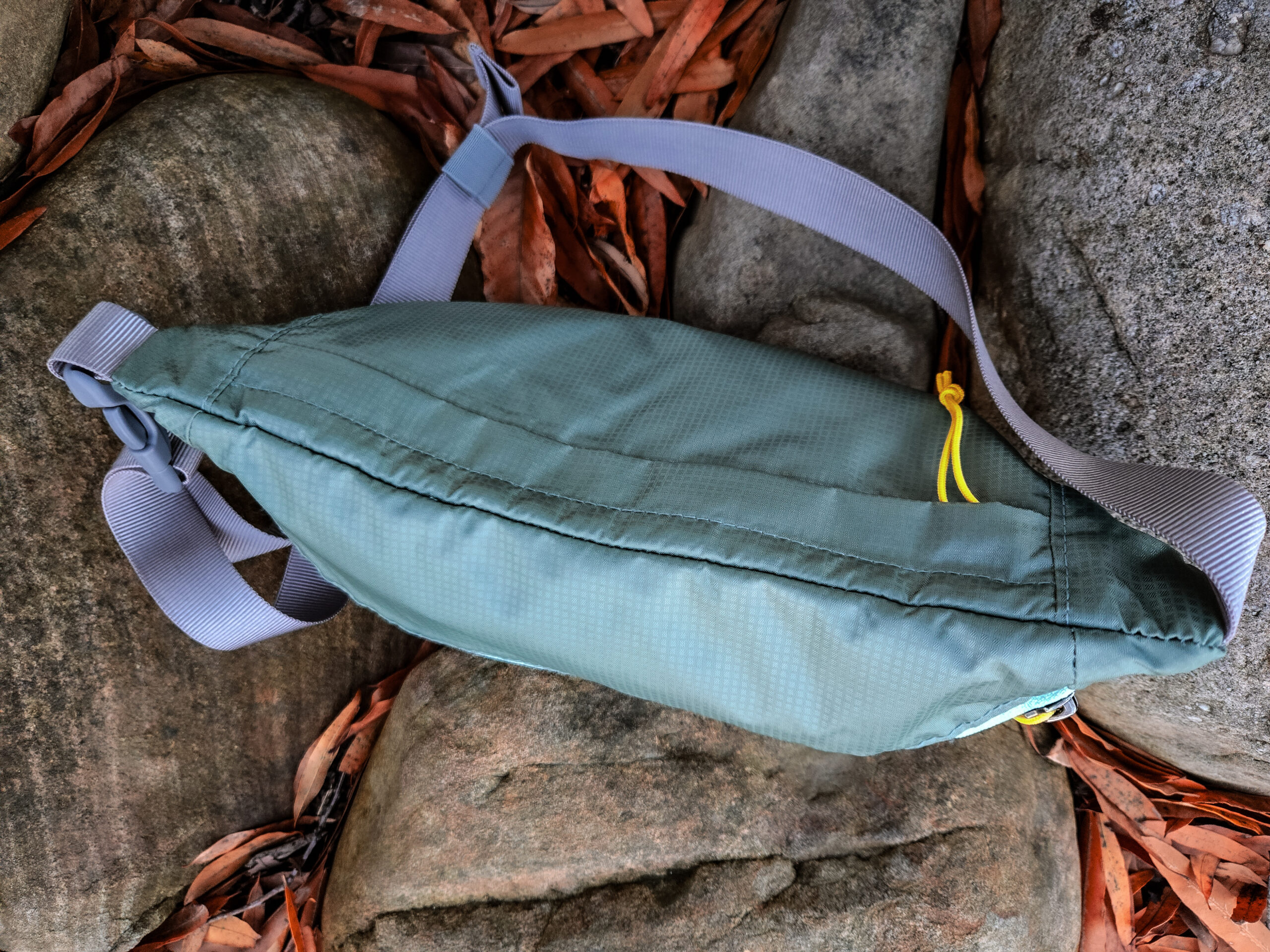 view of the gossamer gear bumster resting on rocks with the zipper showing