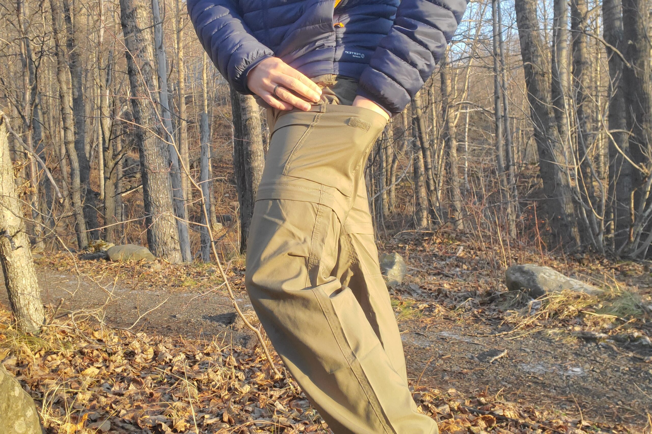 A man puts an item in a velcro cargo pocket on a pair of pants.