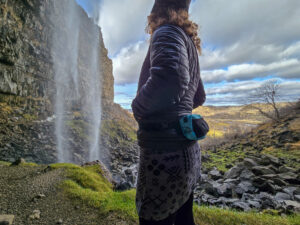 woman wearing a liteaf featherweight fanny pack while walking next to a waterfall