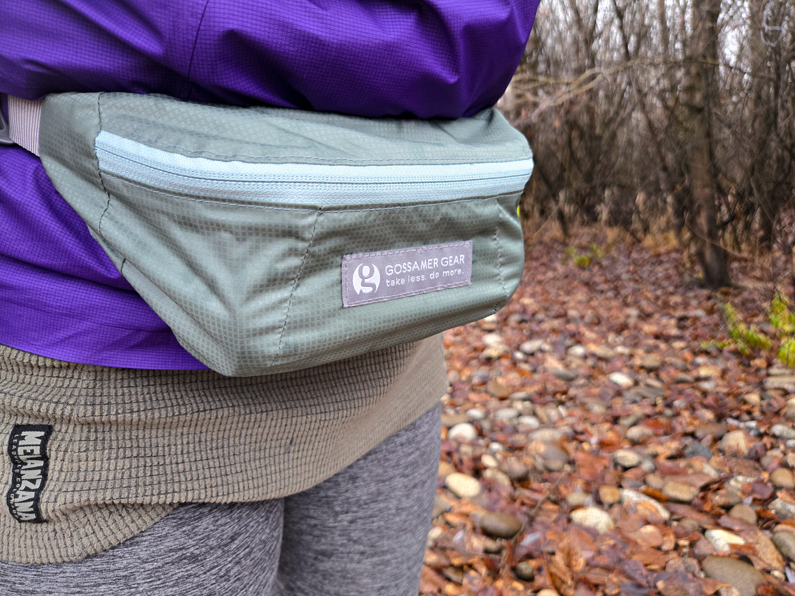 closeup of a woman wearing the gossamer gear bumster on her waist while in a wet forest