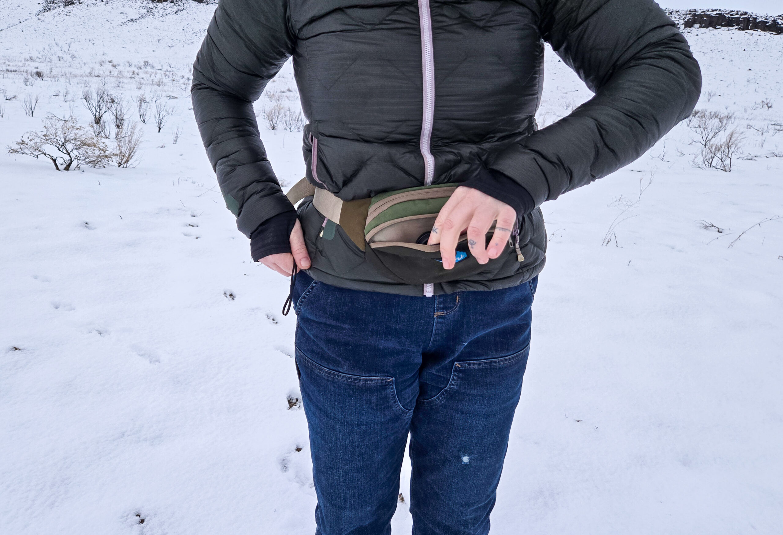 a woman grabbing an item out of her kavu fanny pack