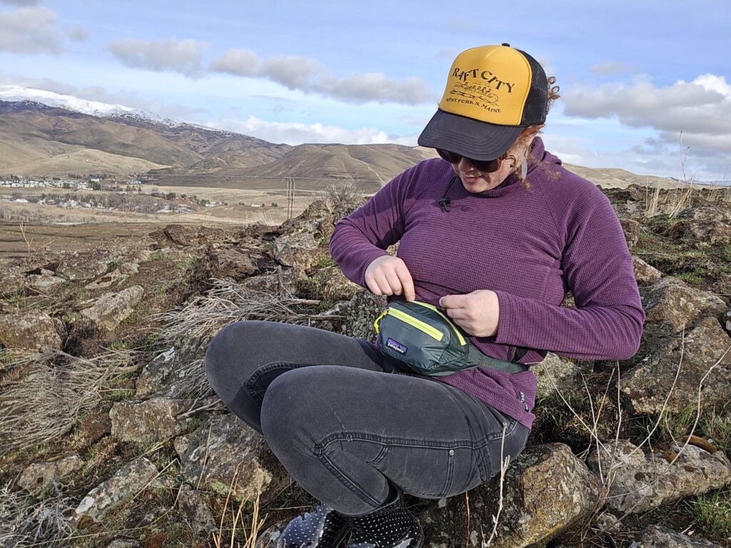 woman unzipping her patagonia black hole fanny pick