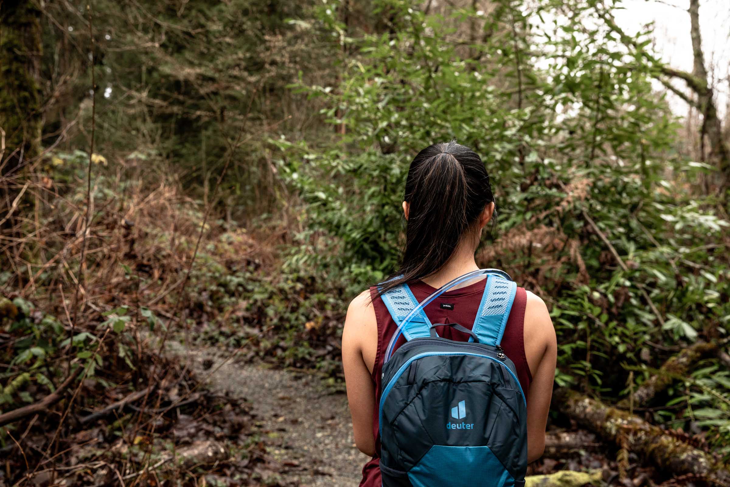 Details of Deuter Speed Lite 13 Hydration Pack - a partial body frame of a person wearing the pack in the forest