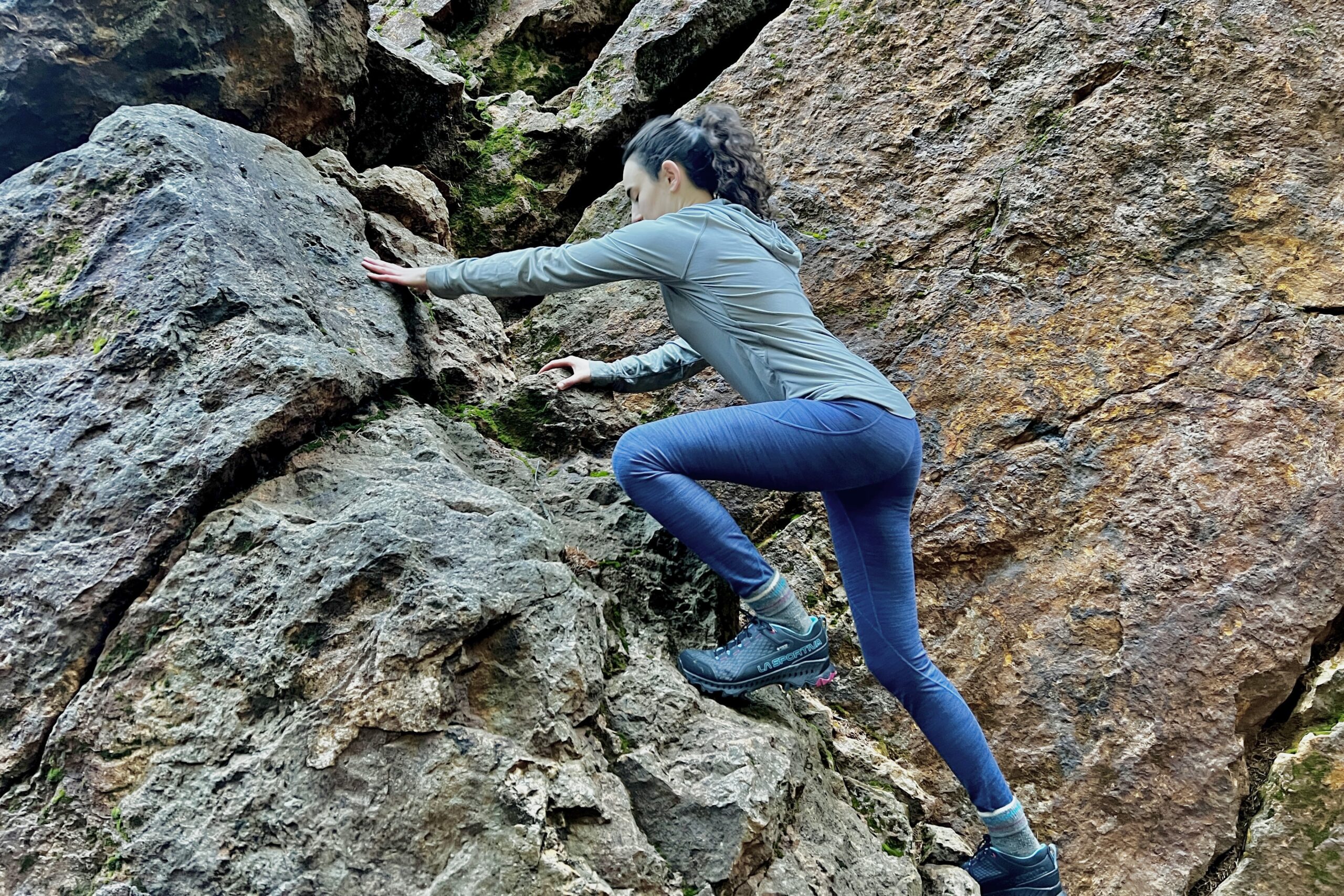 A woman scrambles up a rock in La Sportiva shoes.