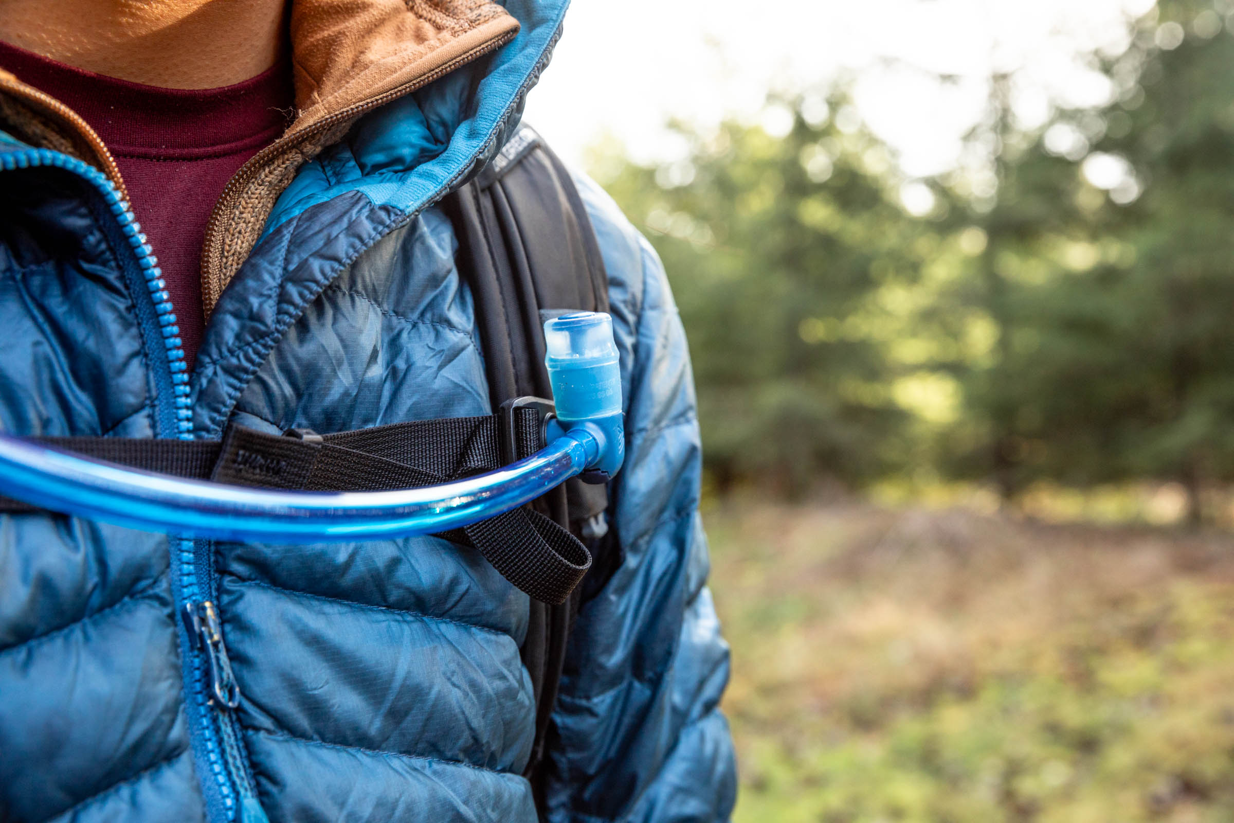 Details of Gregory Sula 16 H2O - close up view of a person wearing the pack with the hydration hose attached to the shoulder strap by a magnet