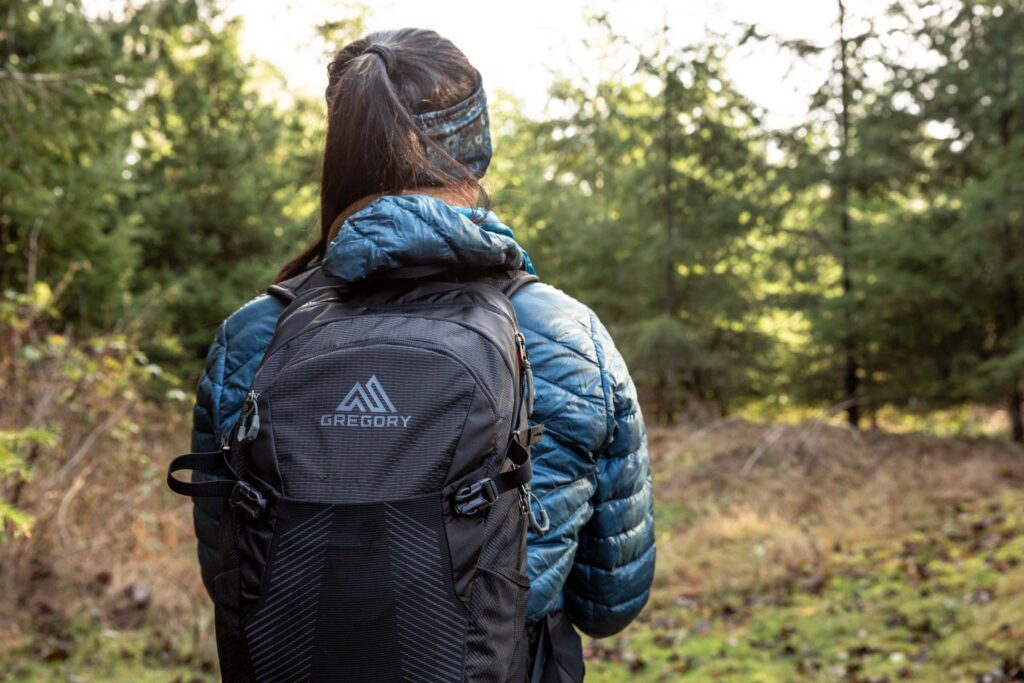 Details of Gregory Sula 16 H2O - a person wearing the pack in nature facing away from the camera