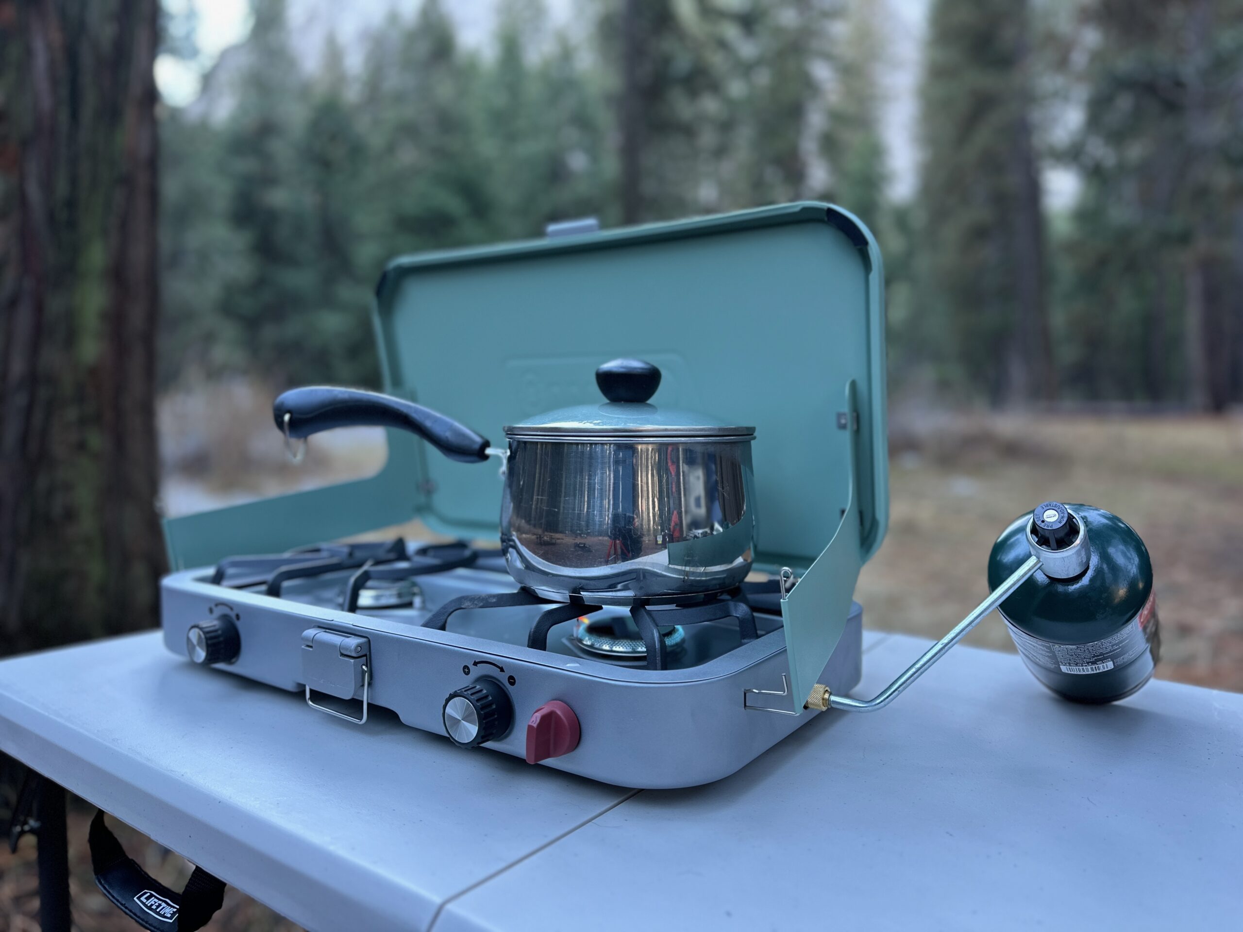 Blue camp stove at forested camp site making rice, burritos, and breakfast. 