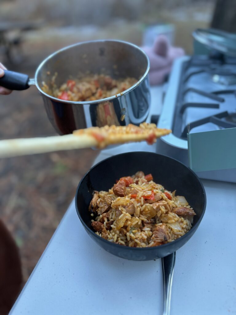 Blue camp stove at forested camp site making rice, burritos, and breakfast. 