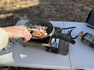 the Gas ONE GS-1000 cooking bacon at camp, showing off how evenly it can cook.