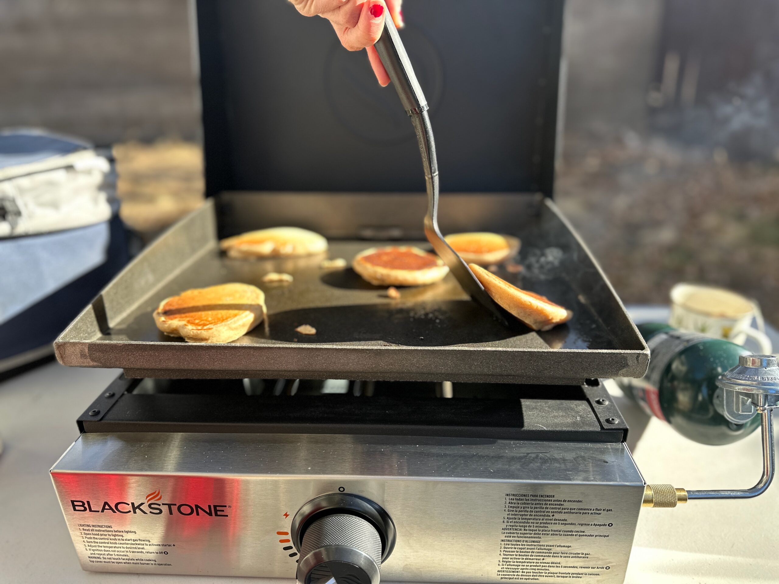 a woman flipping a pancake on the Blackstone Original 17" Tabletop Griddle with Hood