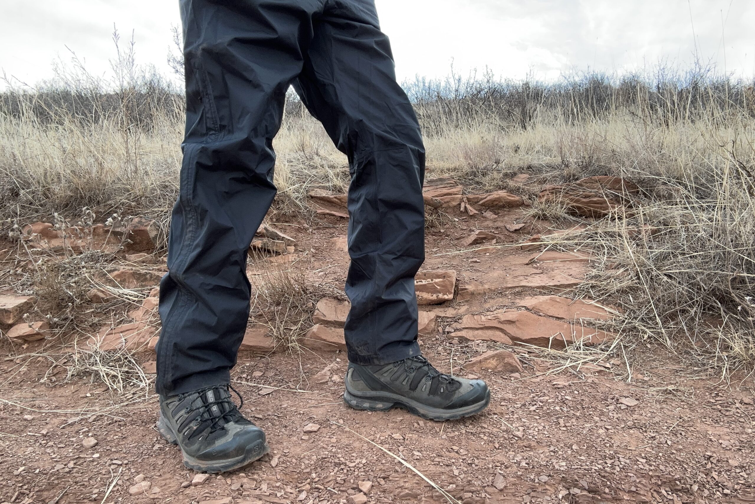 Closeup of someone wearing the black Patagonia Torrentshell rain pants.