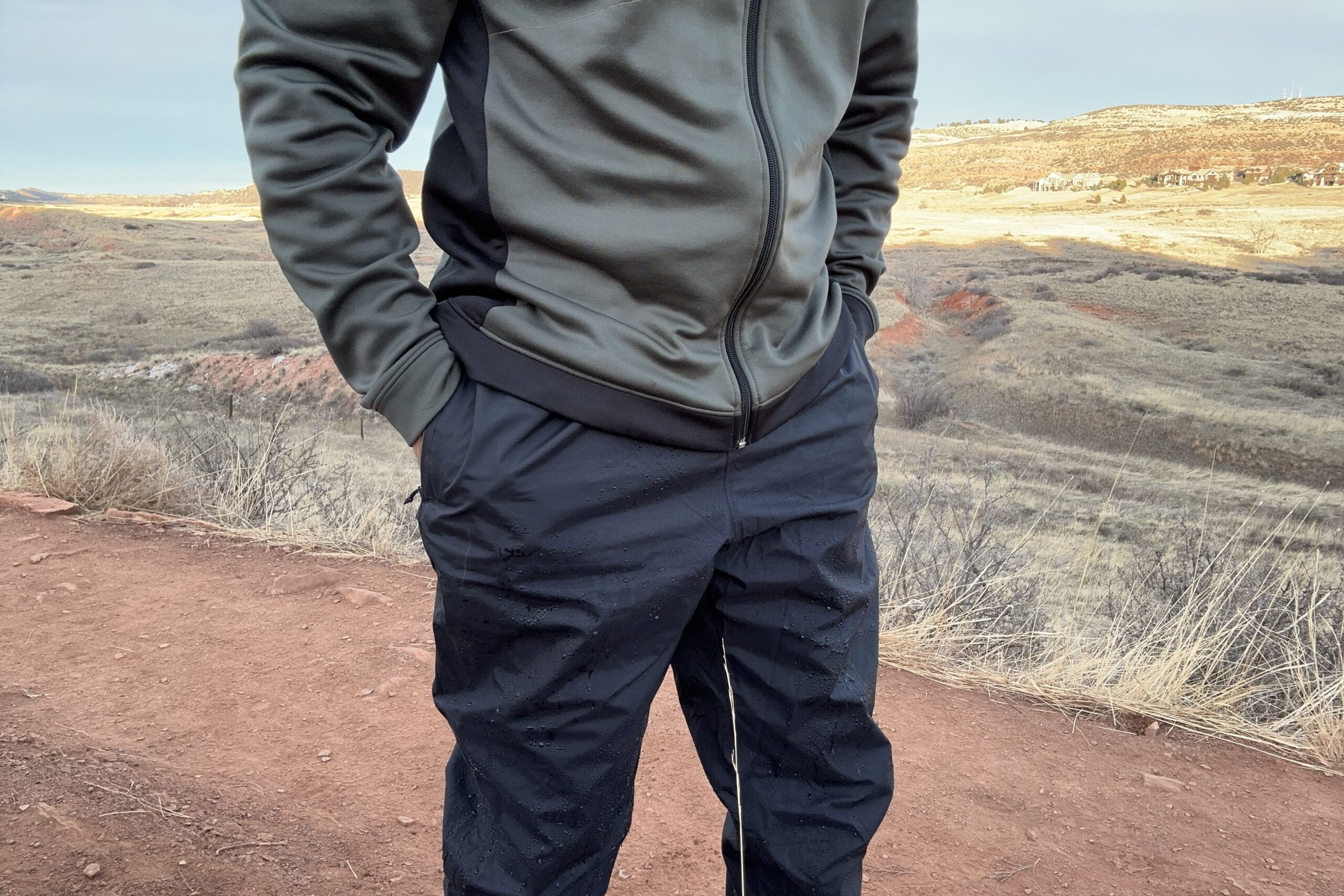 Closeup of someone wearing the black Patagonia Torrentshell rain pants with their hands in the front pockets.