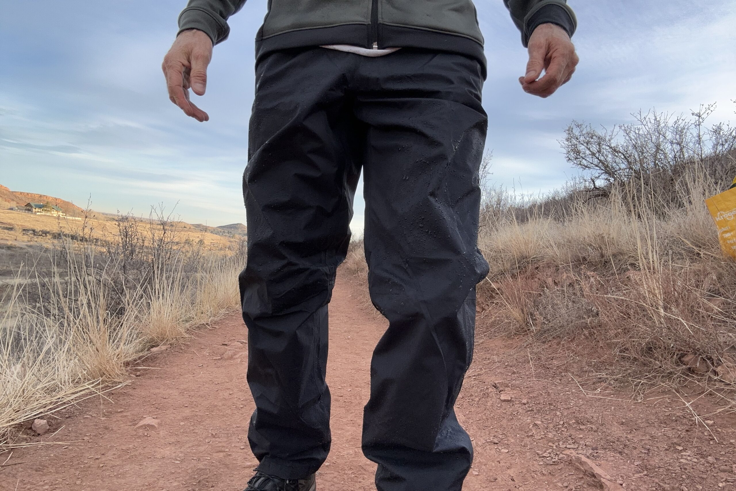 Closeup of someone wearing the black Patagonia Torrentshell rain pants.