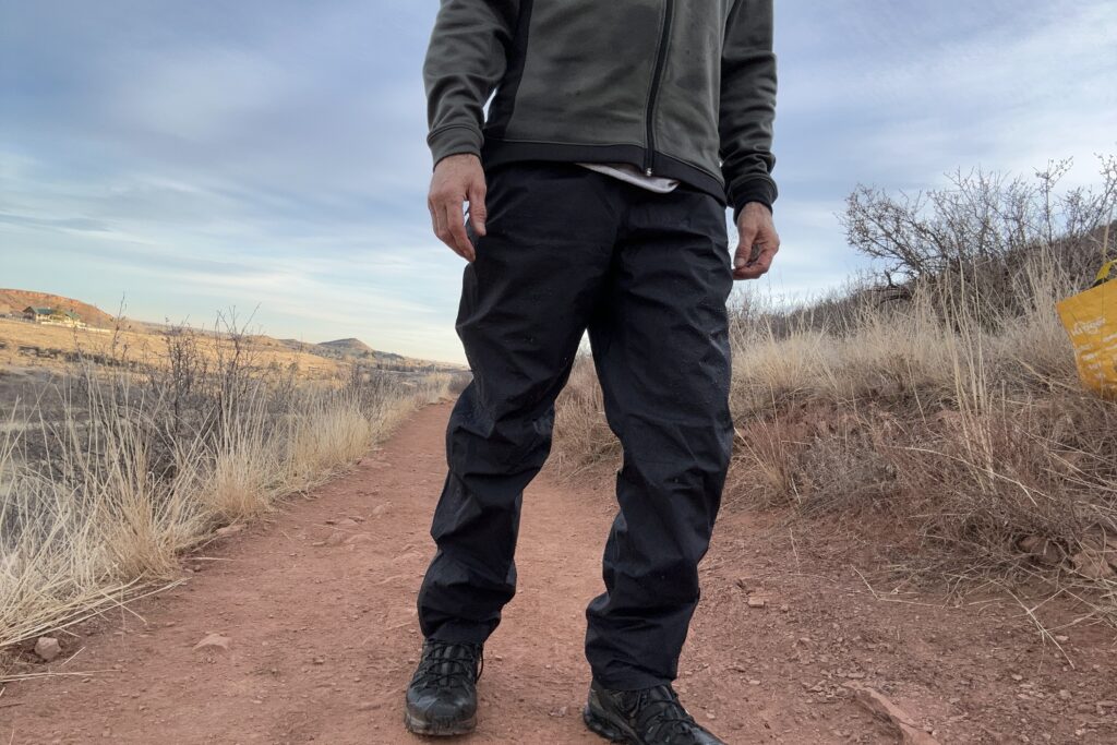 Closeup of someone wearing the black Patagonia Torrentshell rain pants.