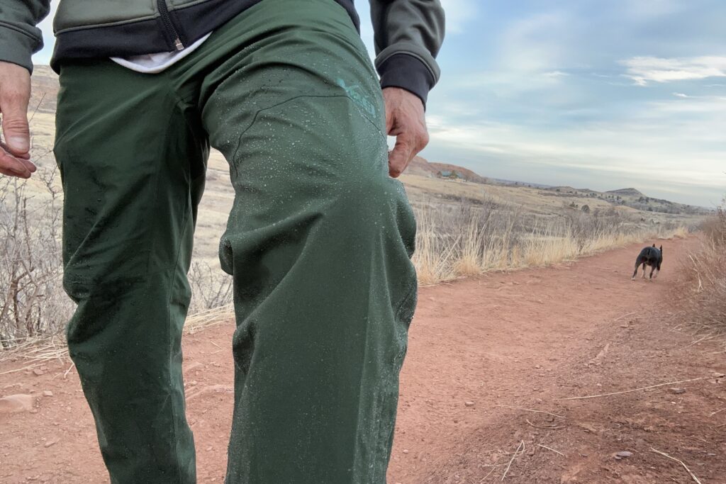 Closeup of someone wearing the green REI Trailmade rain pants.