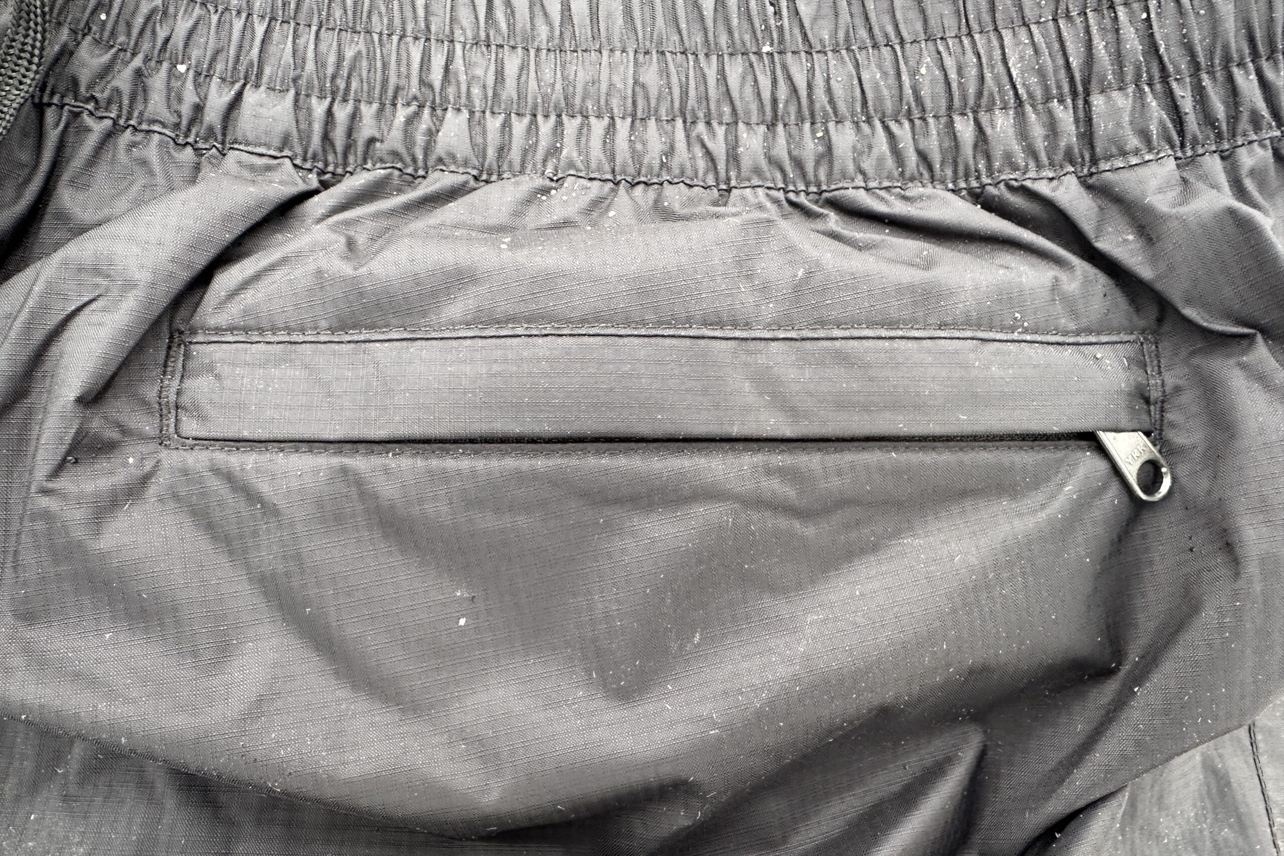 Closeup of the back pocket of the black Marmot PreCip Eco rain pants.