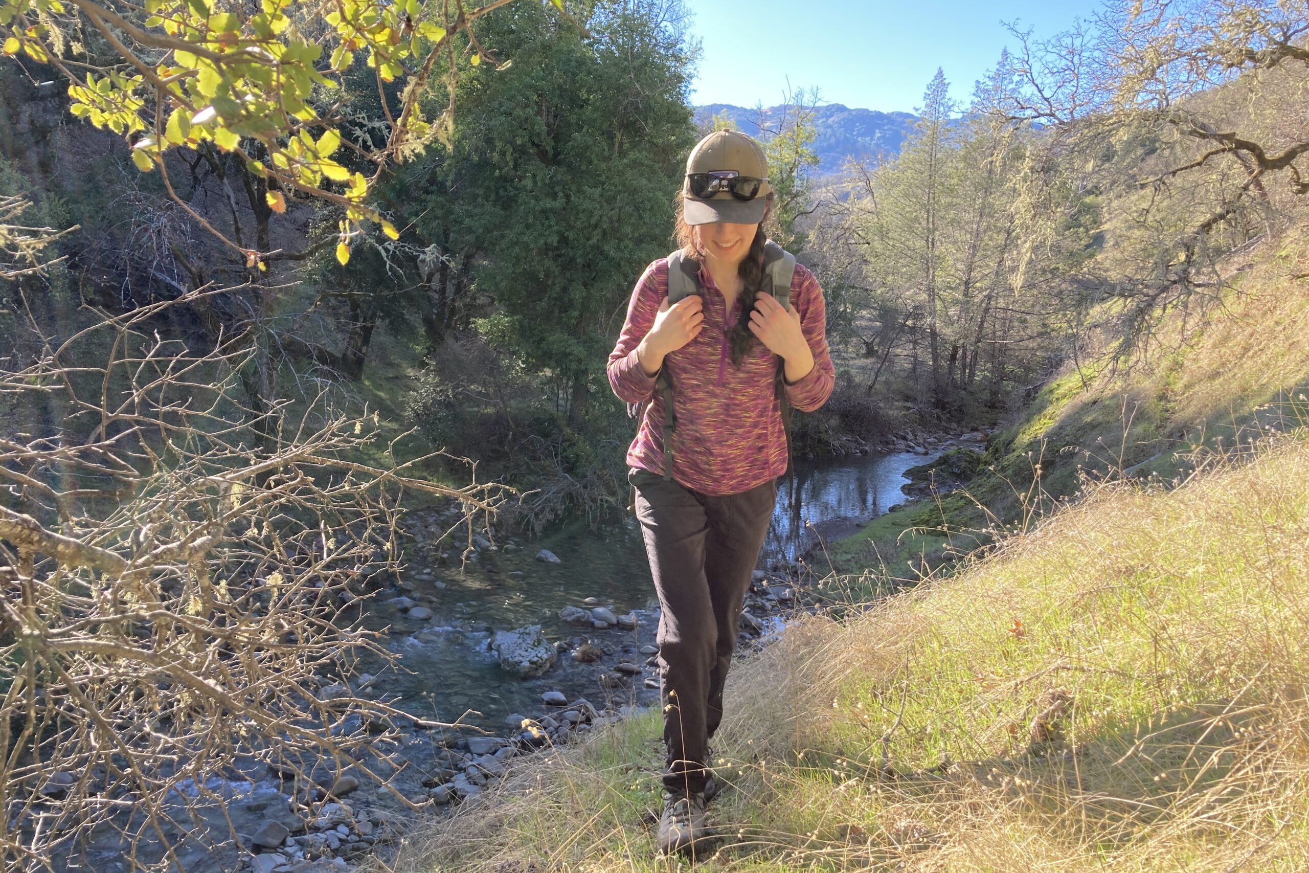 Women hiking on a trail with a creek in the background, wearing Keen hiking shoes.