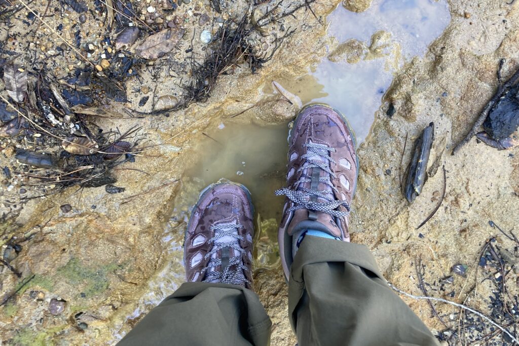 Close-up showing Oboz hiking shoes getting wet in a muddy puddle.