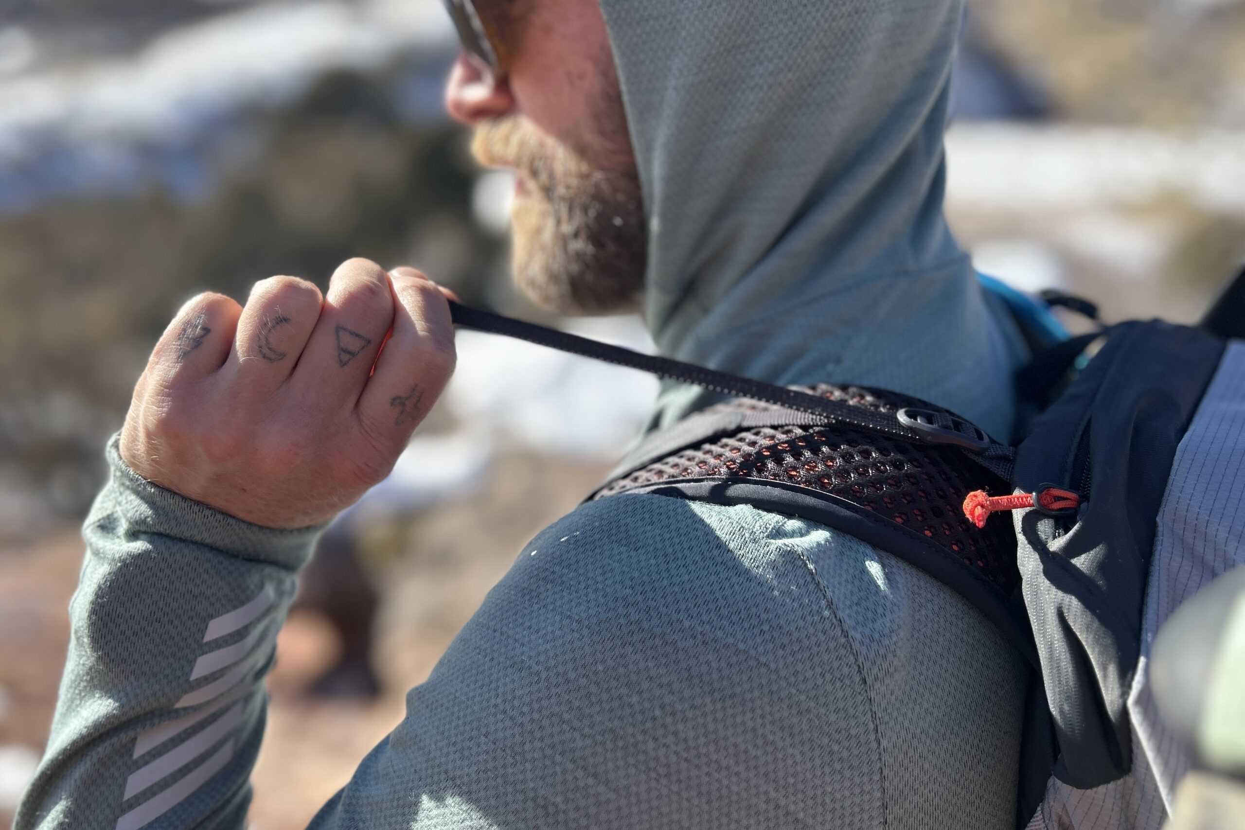 Close up of a person tightening the load lifters on a backpack.