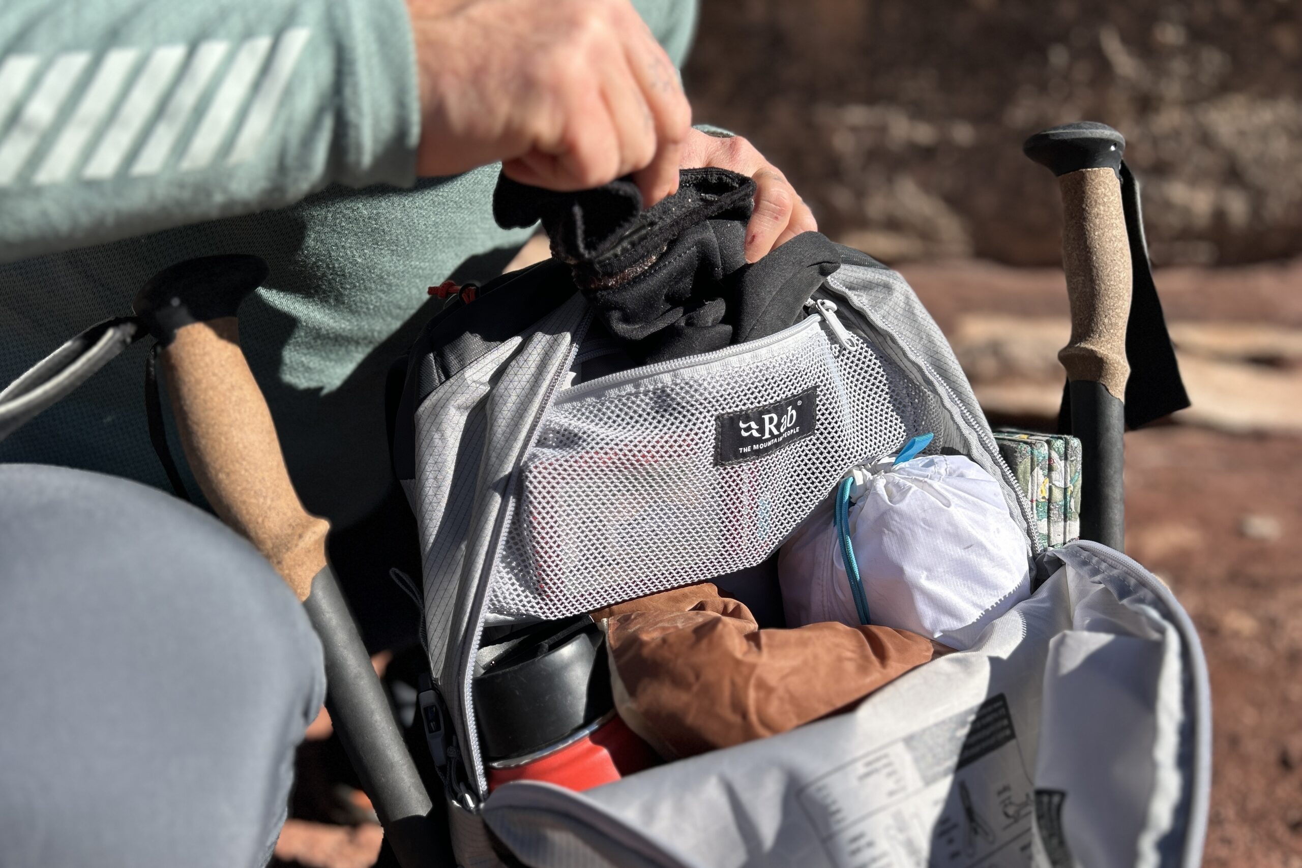 Close up of a person pulling gloves out of a zippered mesh internal pocket with a wallet visible inside.