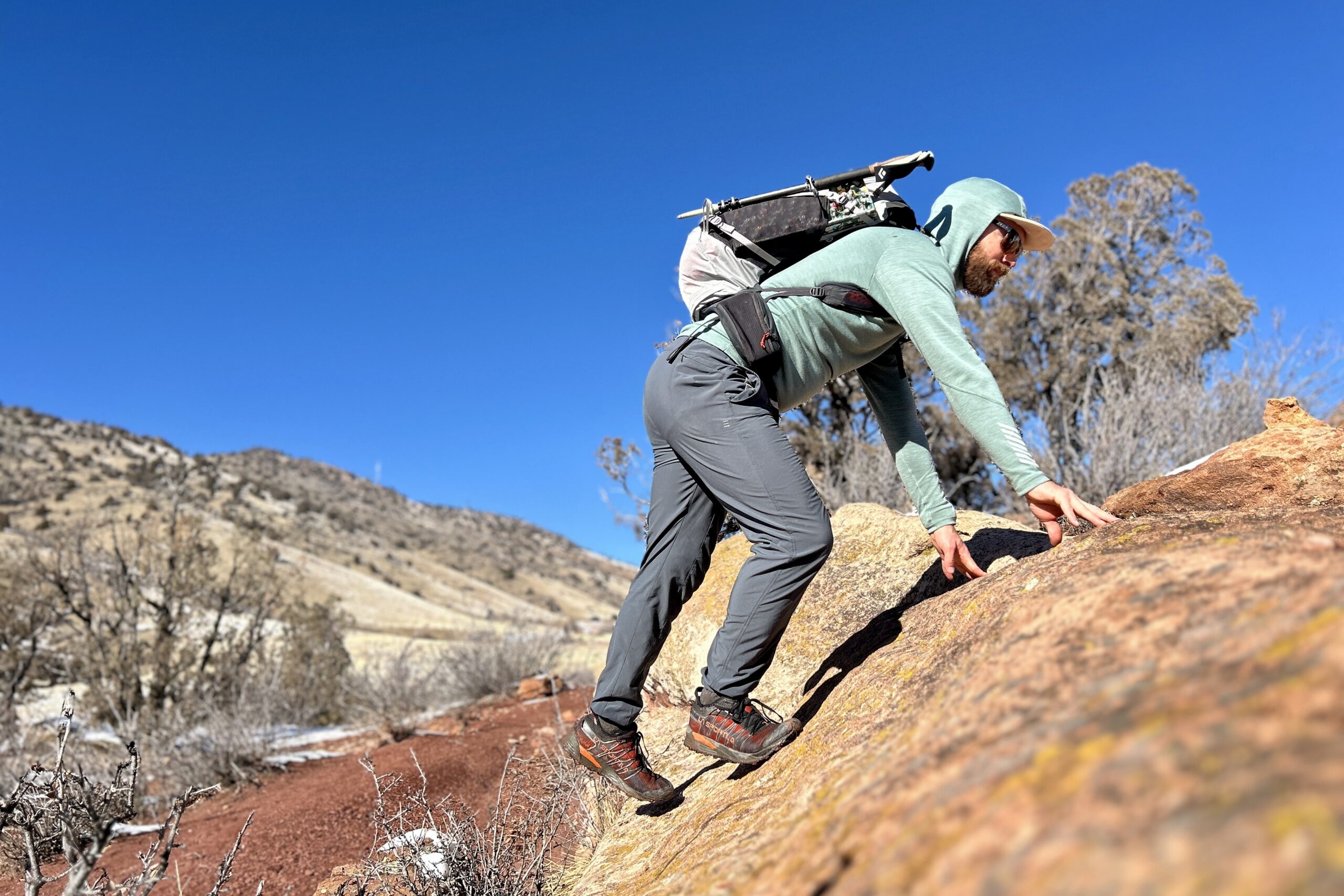 A man scrambles up a rock on a technical hike.